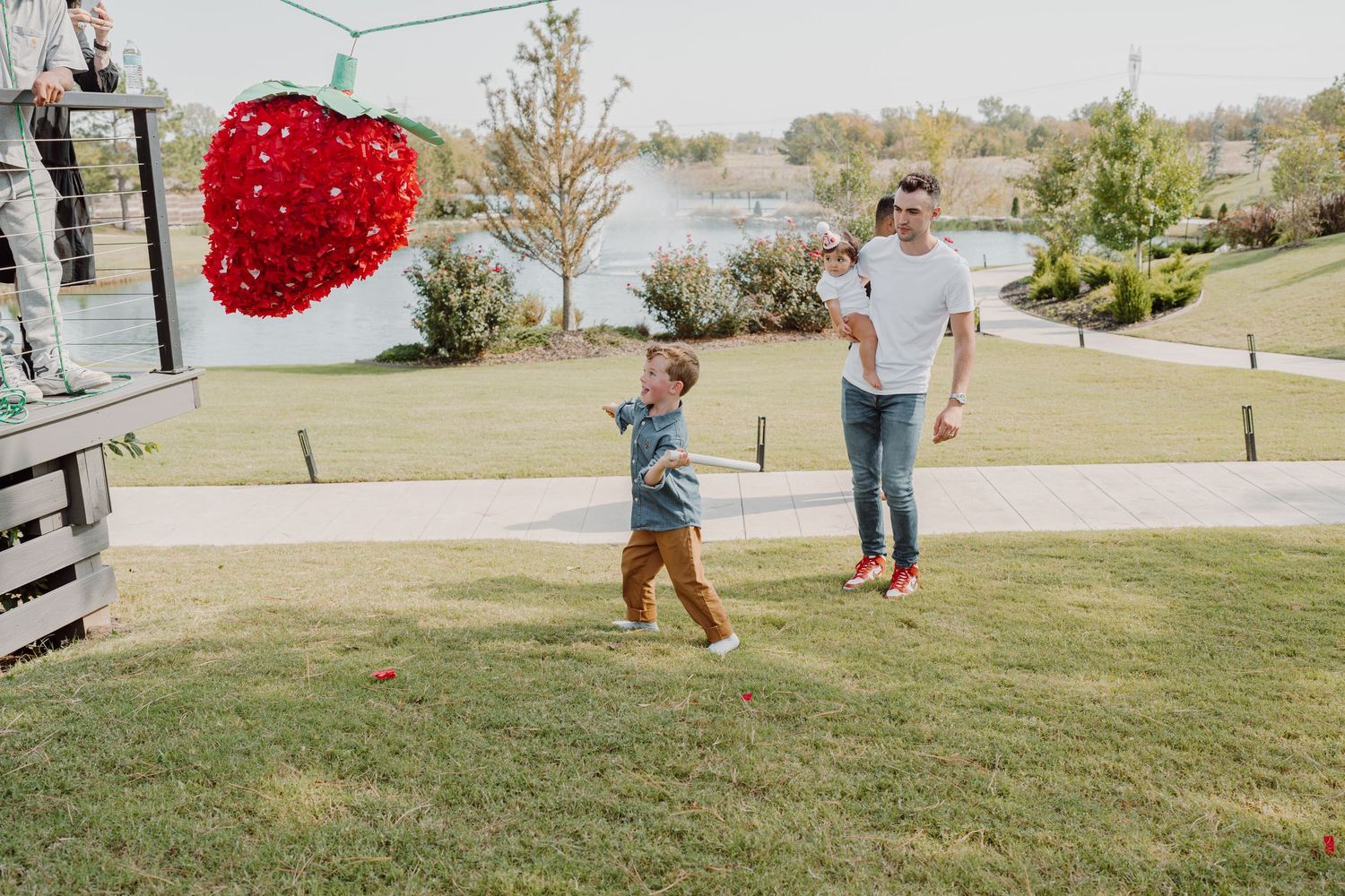 A bright red heart decoration swings between people on a sunny hillside.