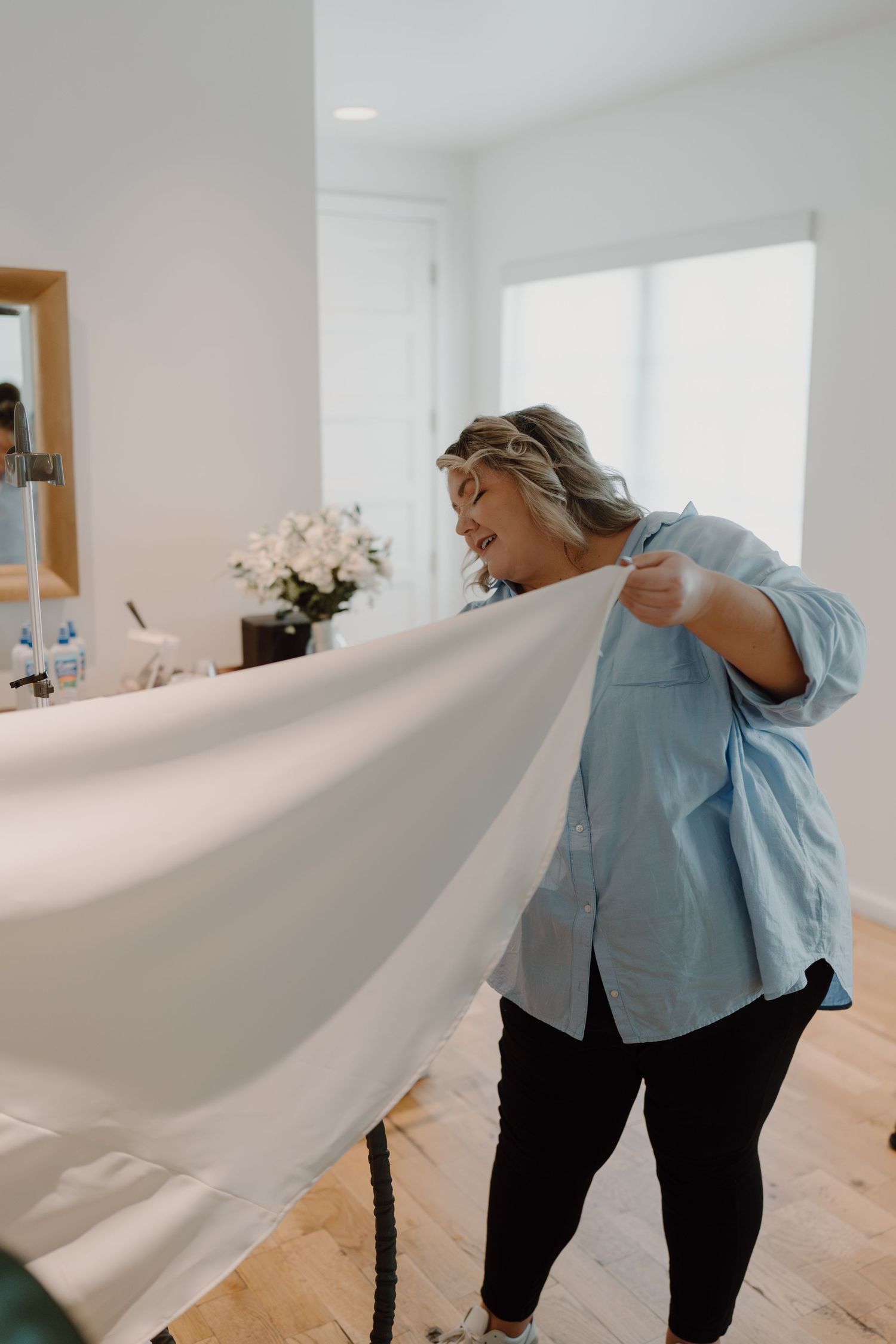 Someone adjusting white fabric in a bright, modern interior space.