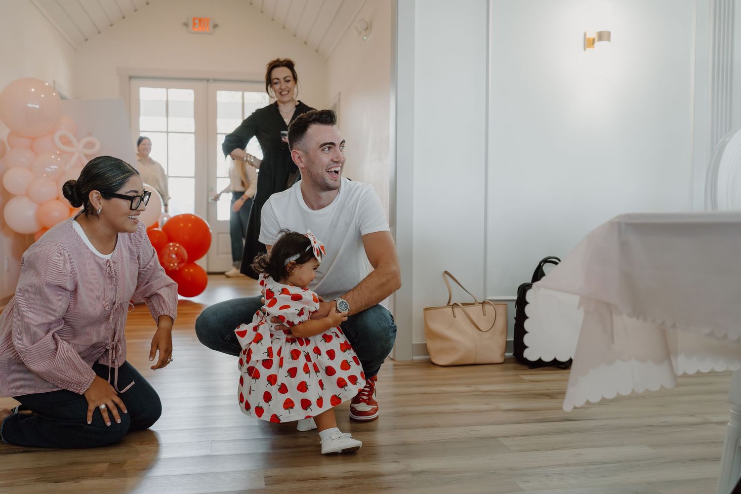 Group posing together on hardwood floors in a bright indoor setting.