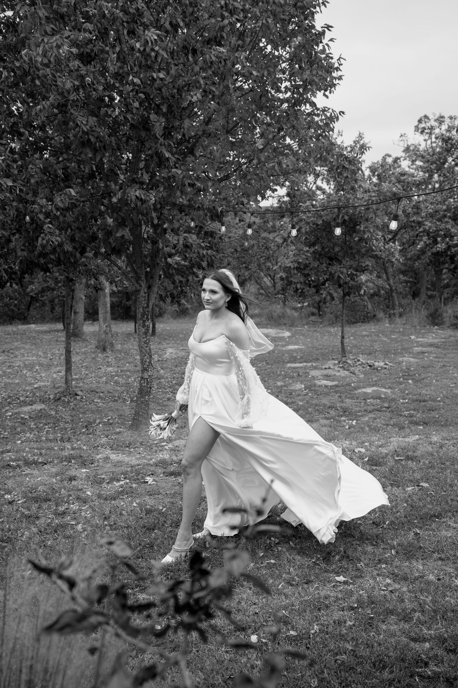 A black and white photo of a flowing wedding dress in motion outdoors.