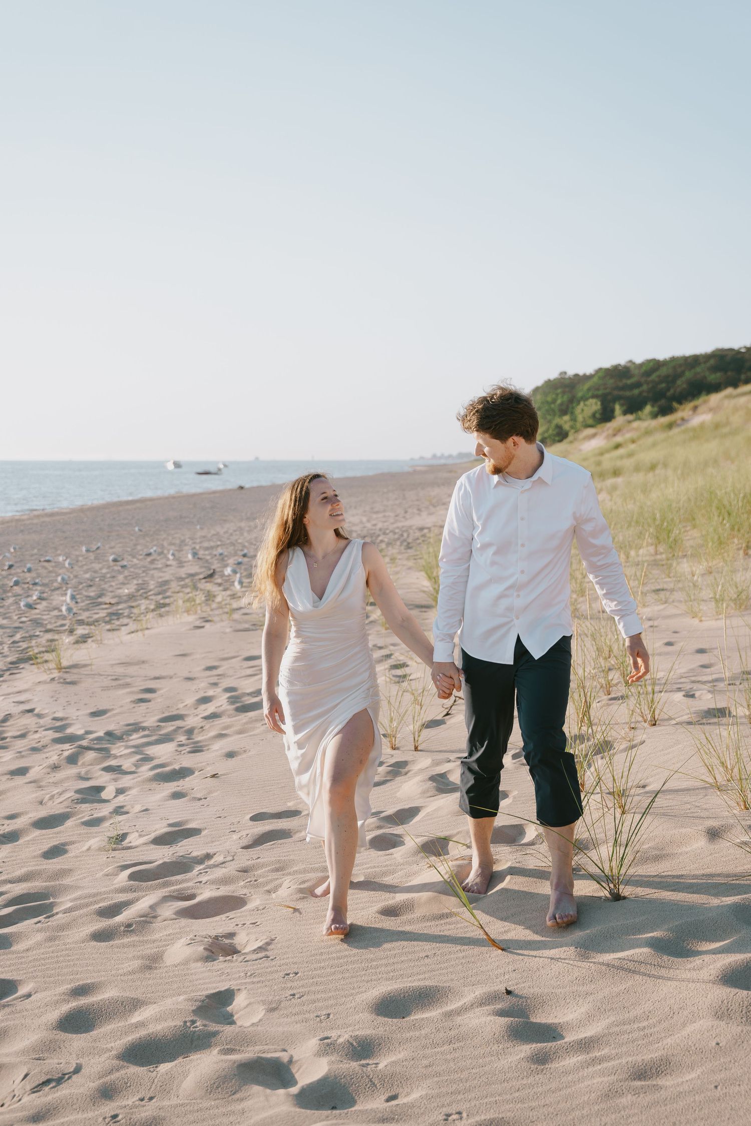 A couple takes a leisurely walk along a scenic coastal beach at sunset.