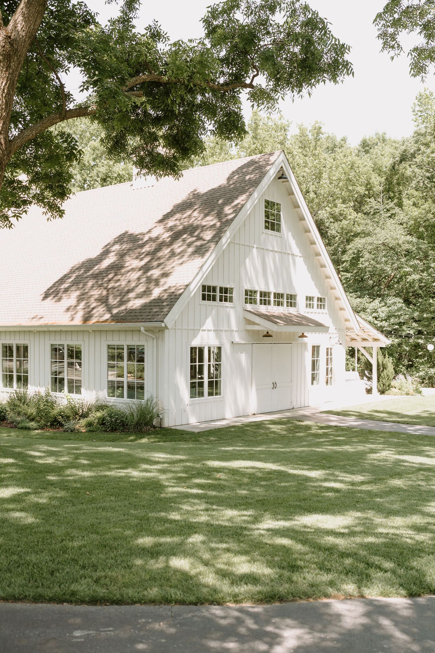 Modern white farmhouse exterior with multiple windows and green lawn.