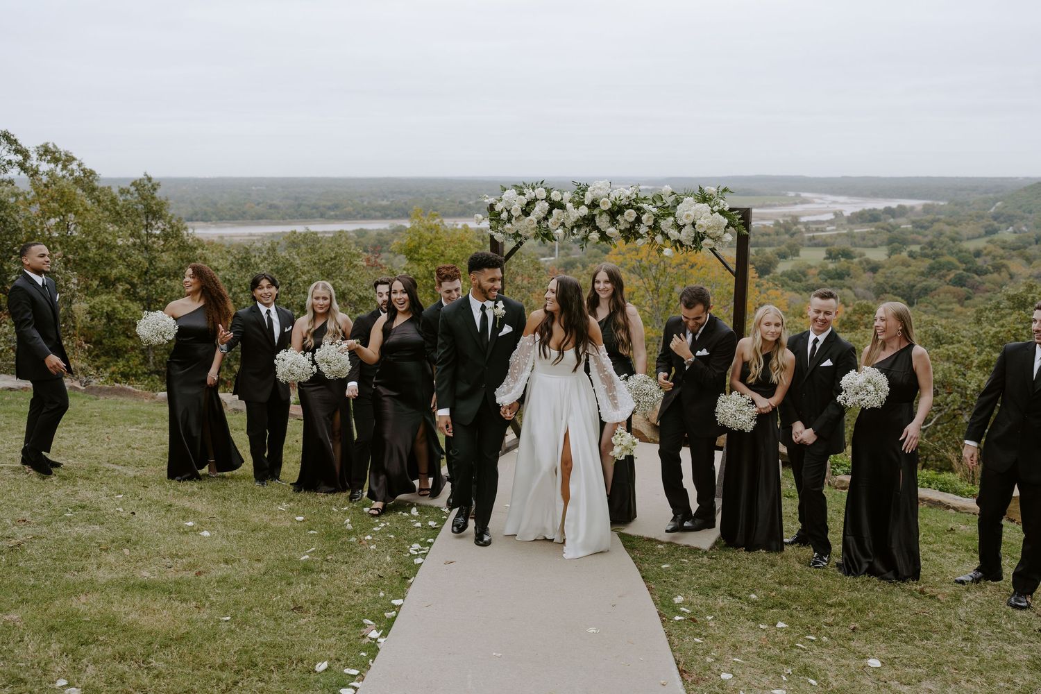 Panoramic view of wedding guests gathered along a white pathway on a scenic overlook.