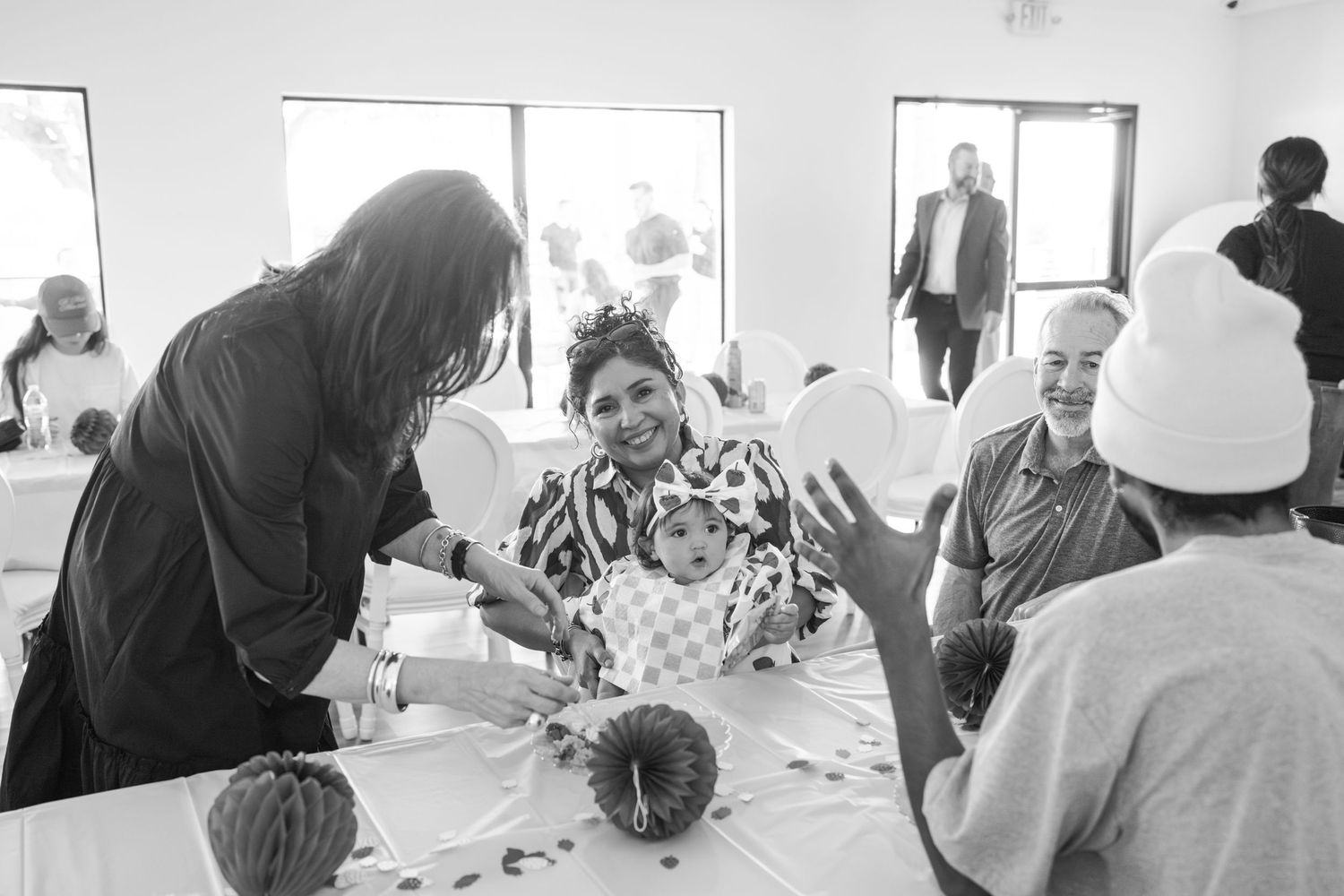 Party guests seated at tables in bright room with large windows.