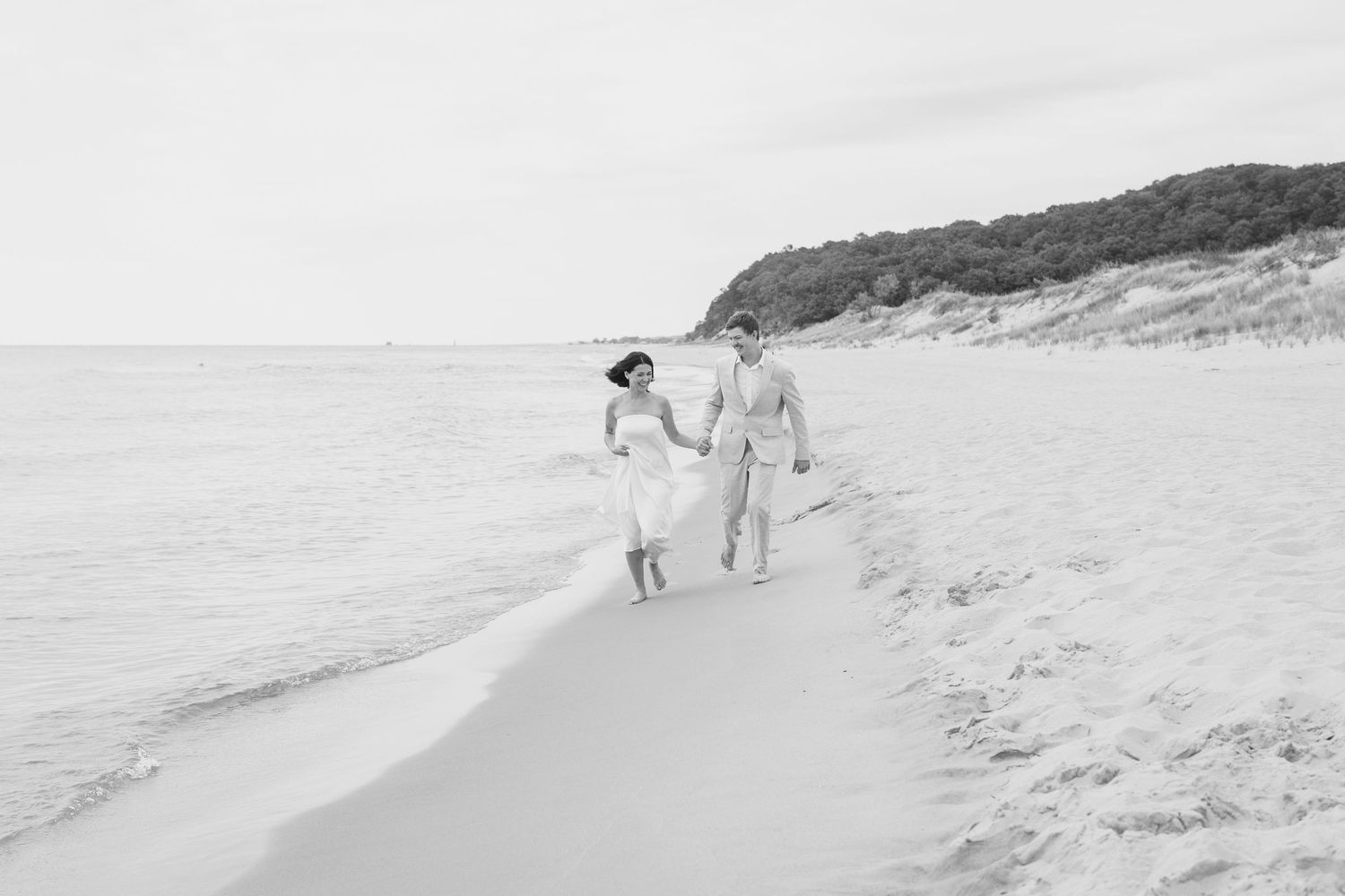 Distant silhouettes walking along a scenic beach with green cliffs in the background.