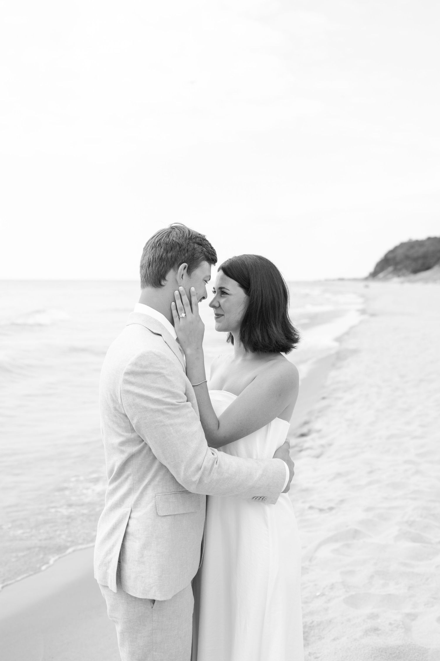 A black and white portrait of a couple sharing an intimate moment on the beach.