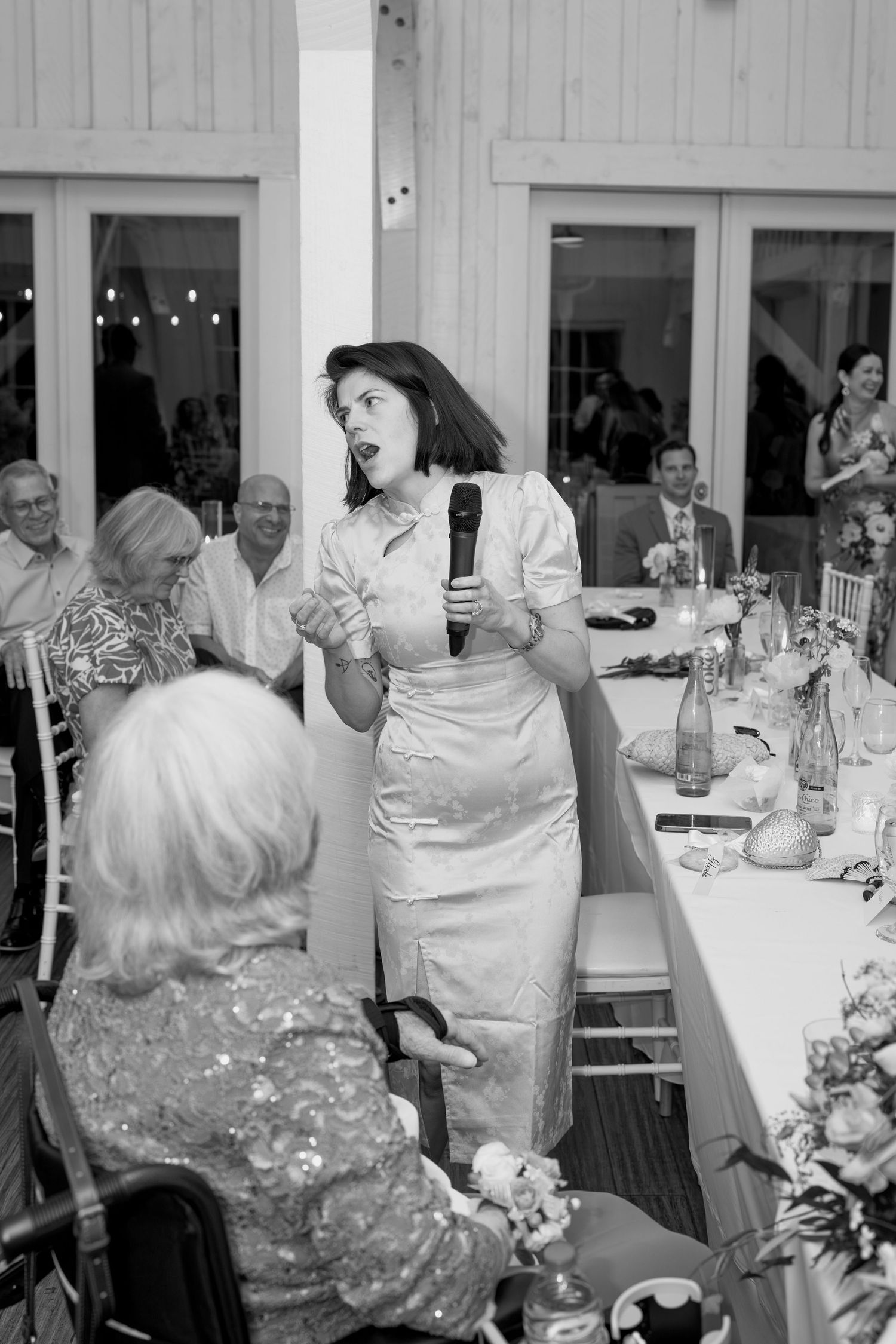 Wedding guests celebrating and dancing during reception in white venue.