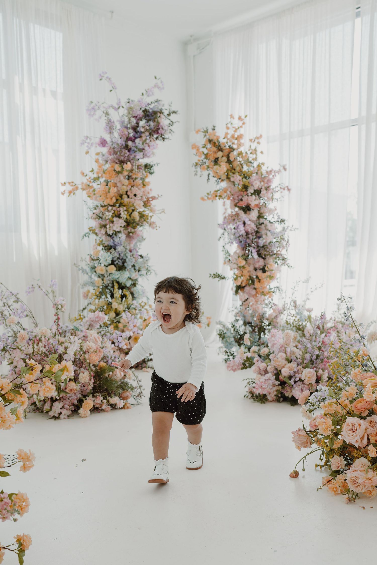 Candid moments captured in a light-filled studio with lush floral arrangements in soft spring colors.