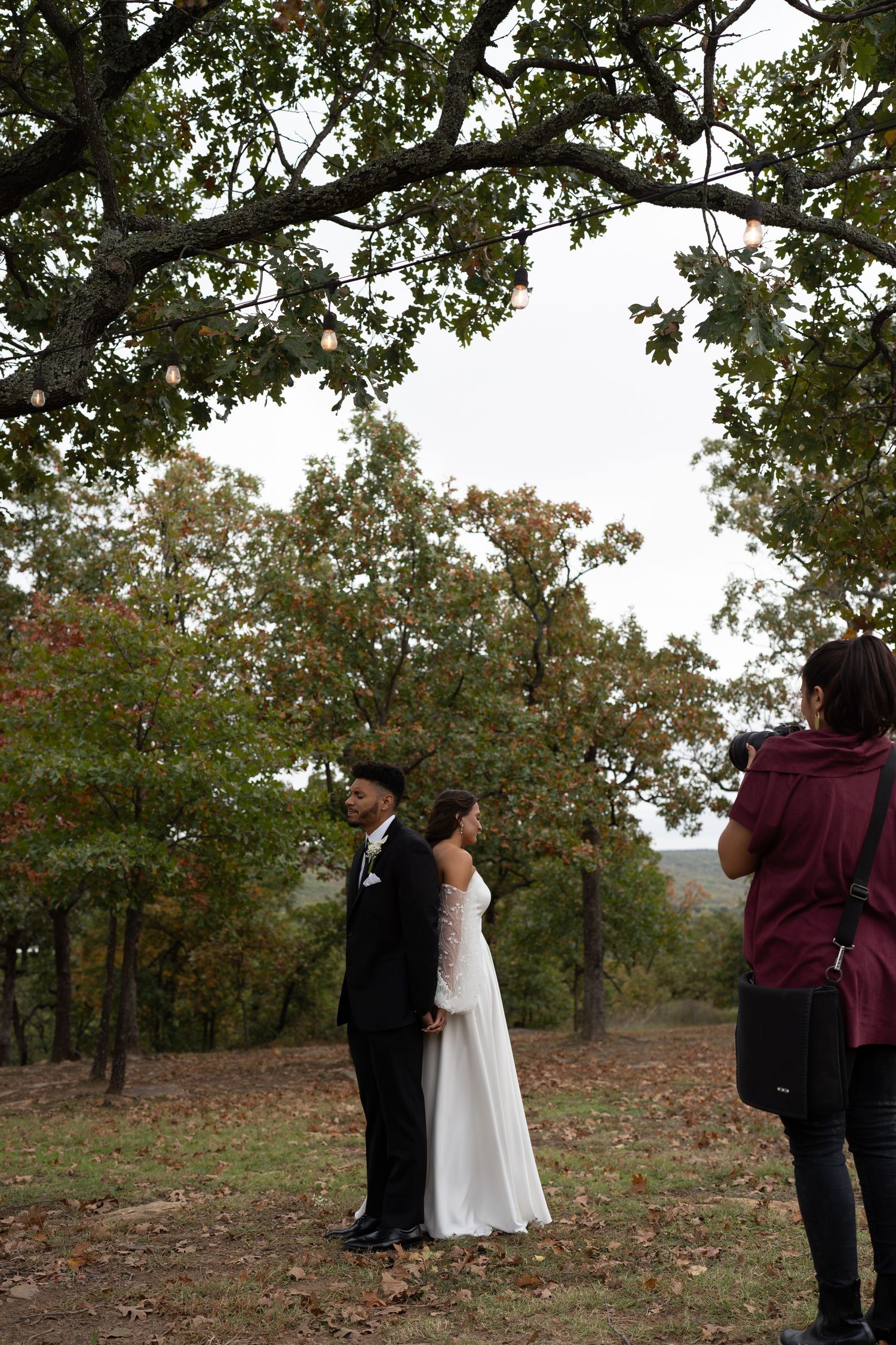A couple embraces during their autumn wedding photoshoot among trees.