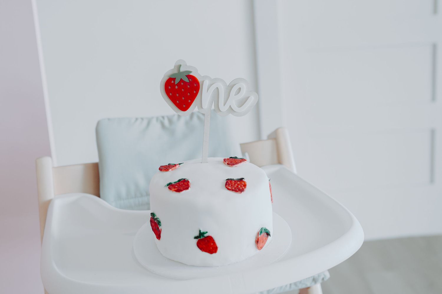 White cake decorated with small strawberry designs and red accents.