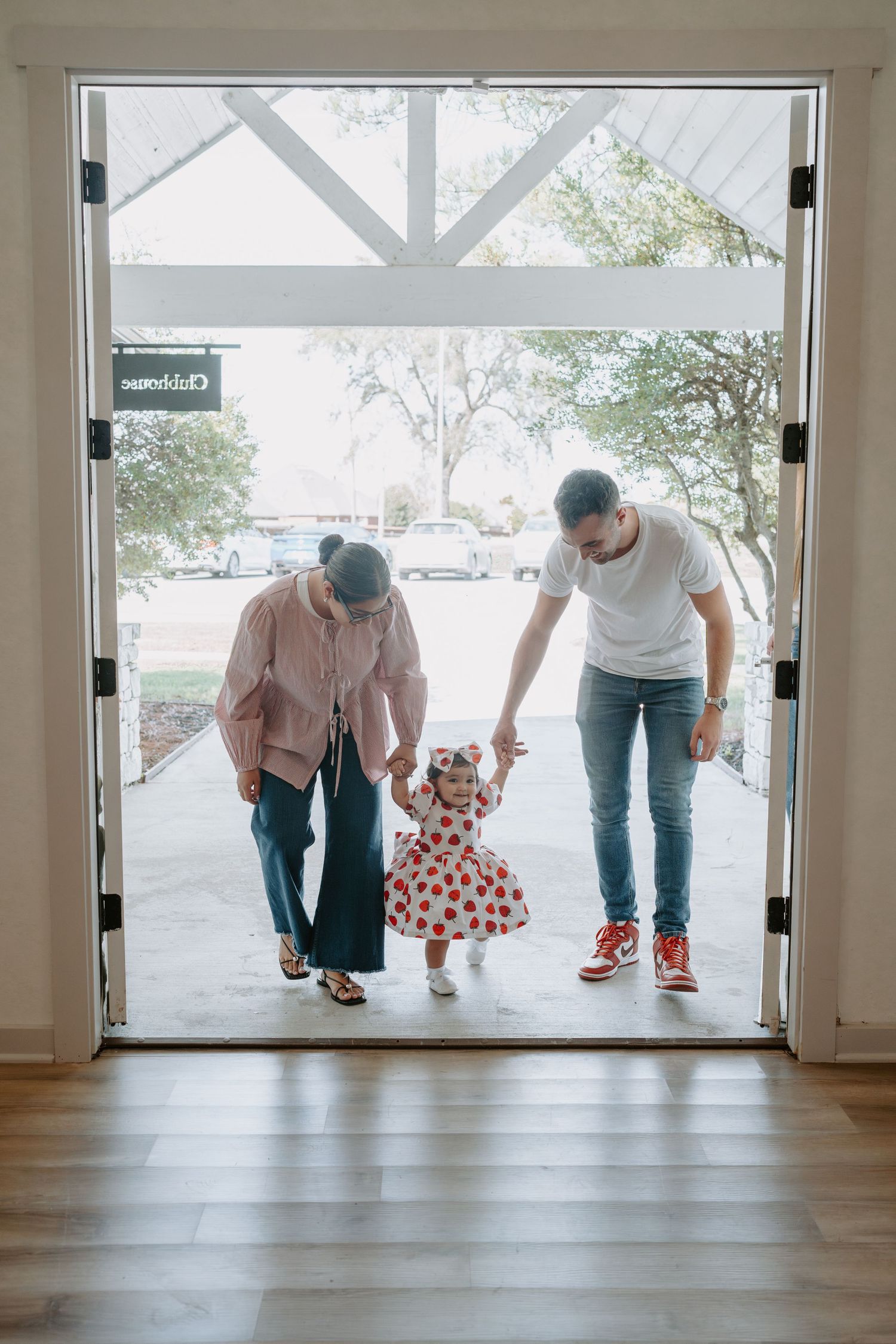People visible through large glass doors in an empty room with wooden floors.