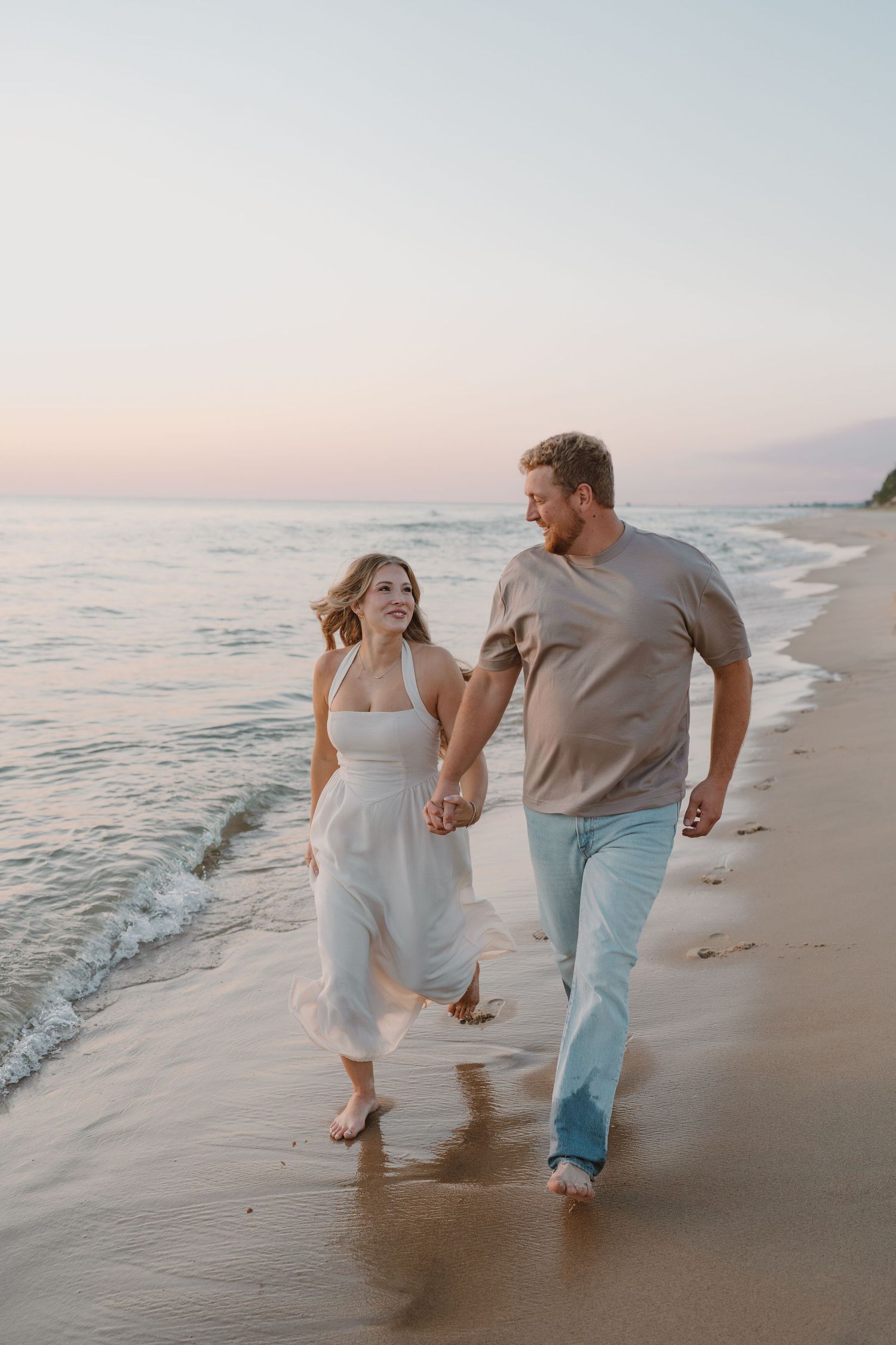 Playful couple running and splashing along the beach at dusk.