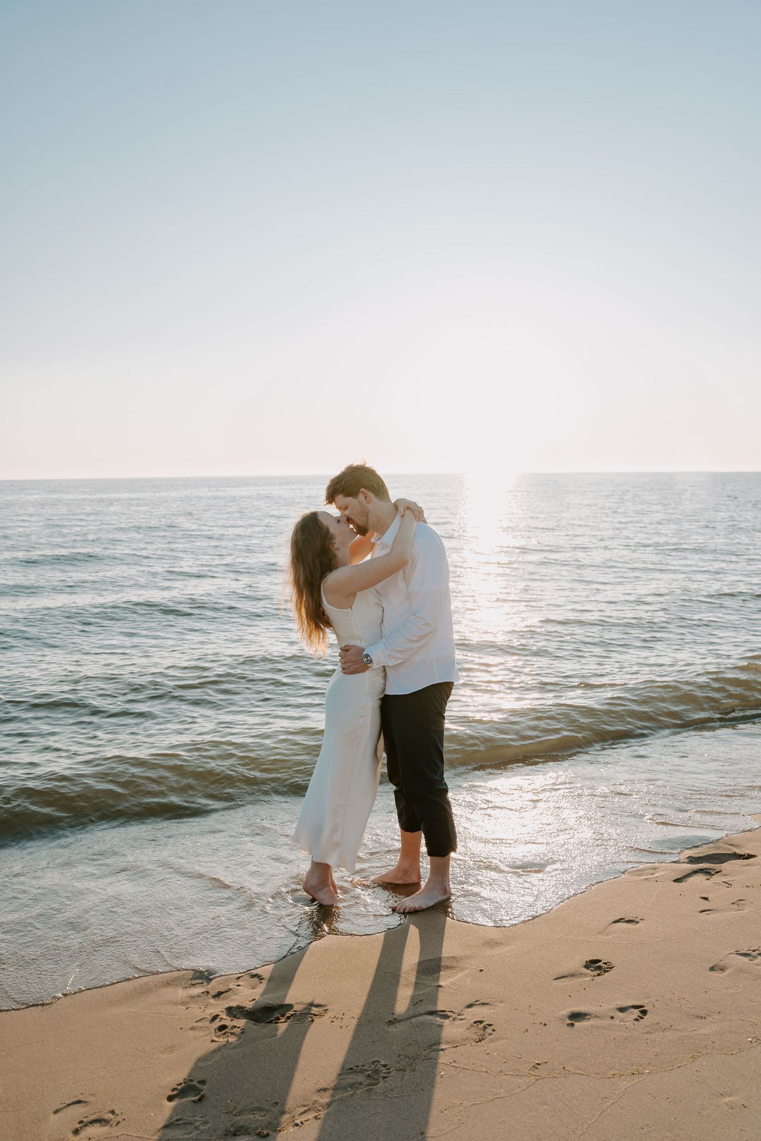 A romantic embrace on the beach with the sunset glowing over the ocean.
