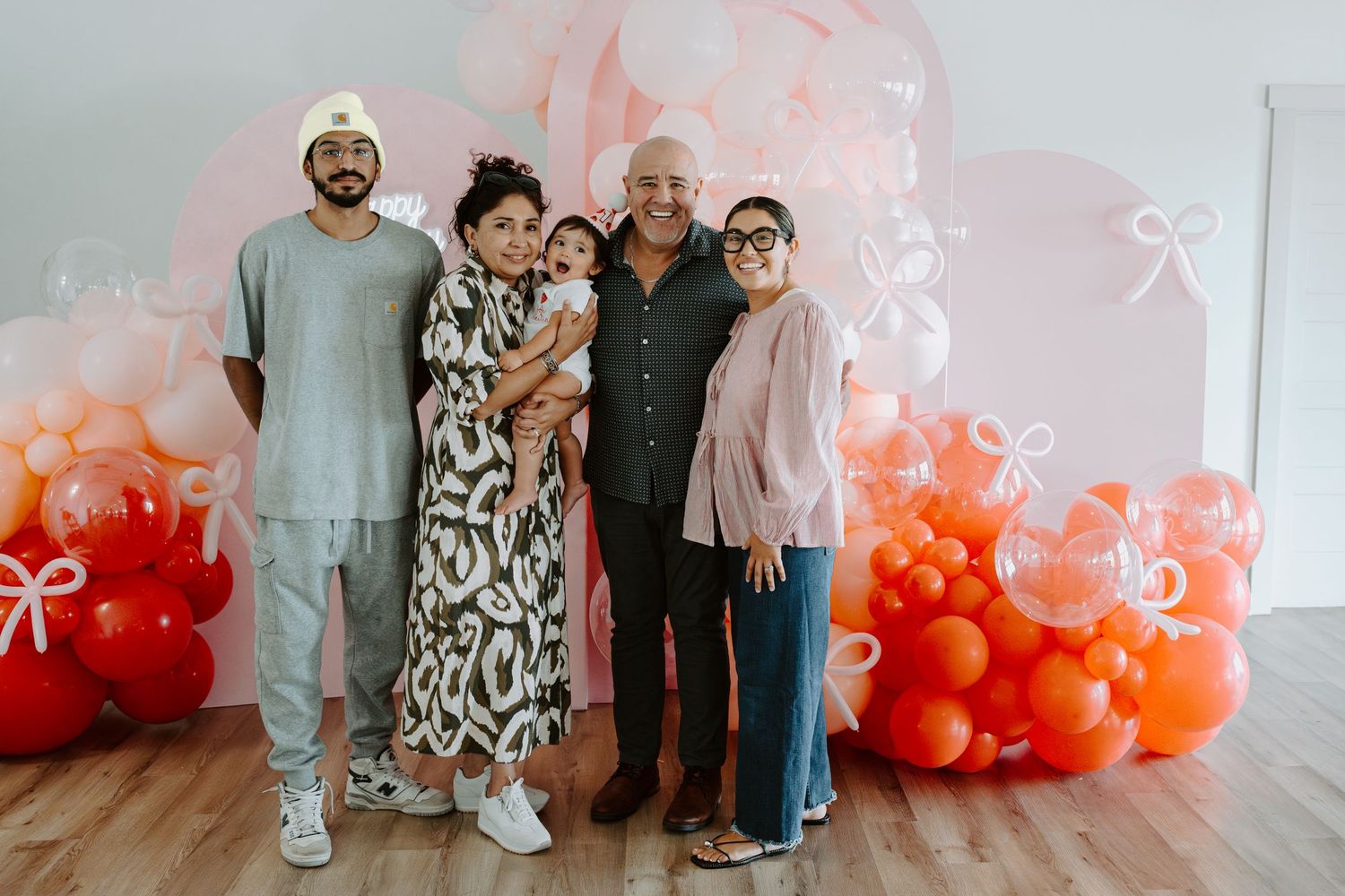 Celebratory photo with family members beside a pink and coral balloon arrangement.