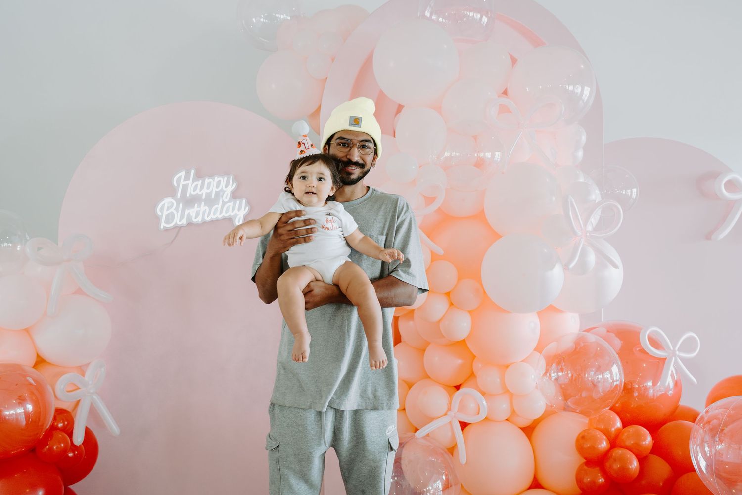 Birthday celebration setup with whimsical balloon arch in pink and orange hues.