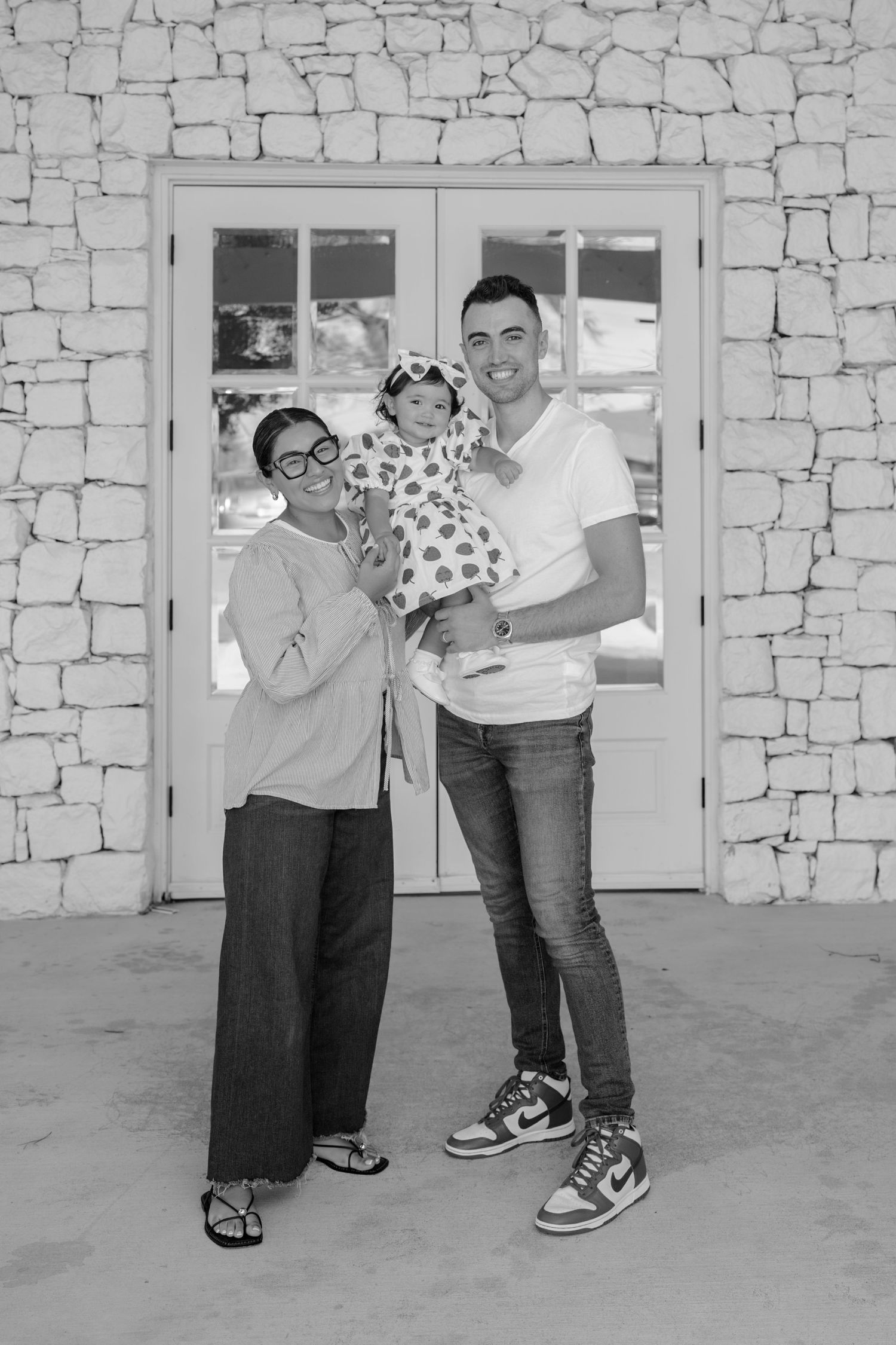 Black and white photo of playful poses against textured stone wall background.