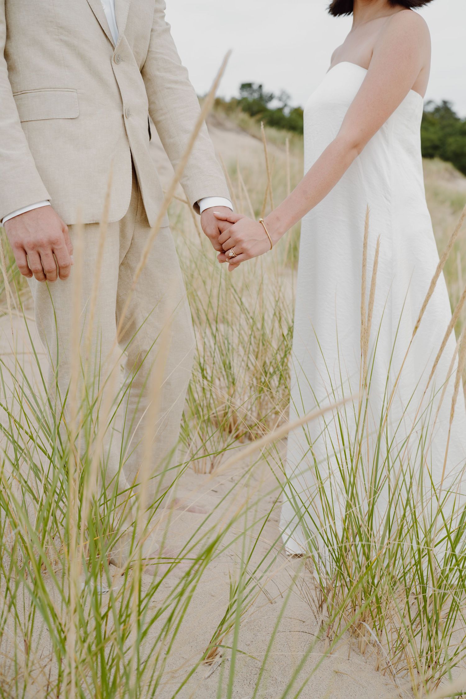 Intimate beach portrait showing formal attire details against coastal vegetation.