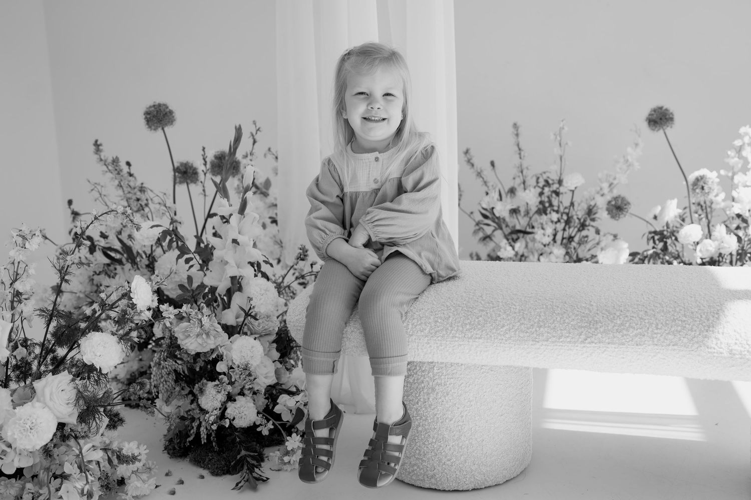 Candid moment captured on a white ottoman with artistic flower arrangements.