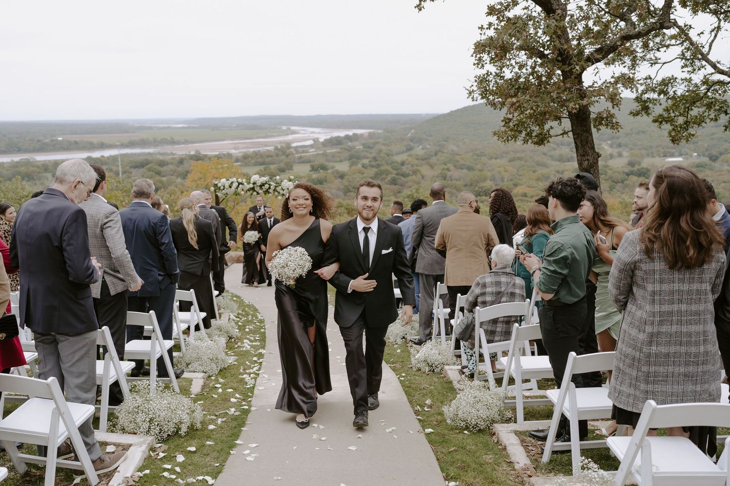 Wedding ceremony setup with white chairs arranged on a hilltop overlooking a scenic landscape view.