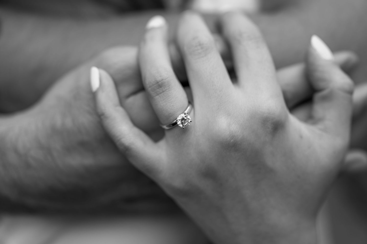 Close-up shots of hands with an engagement ring in black and white.