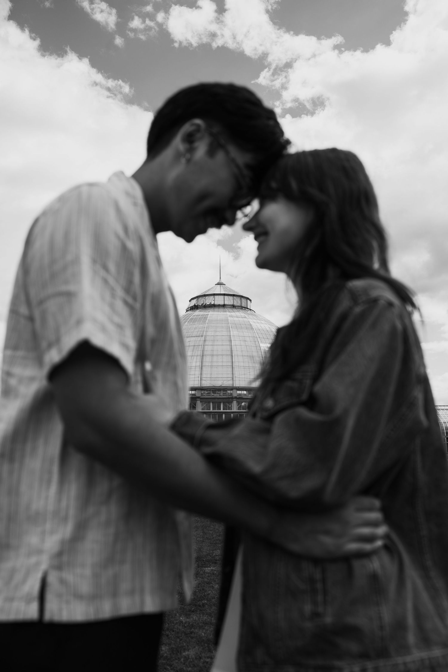Romantic silhouettes against cloudy sky with conservatory building in background.