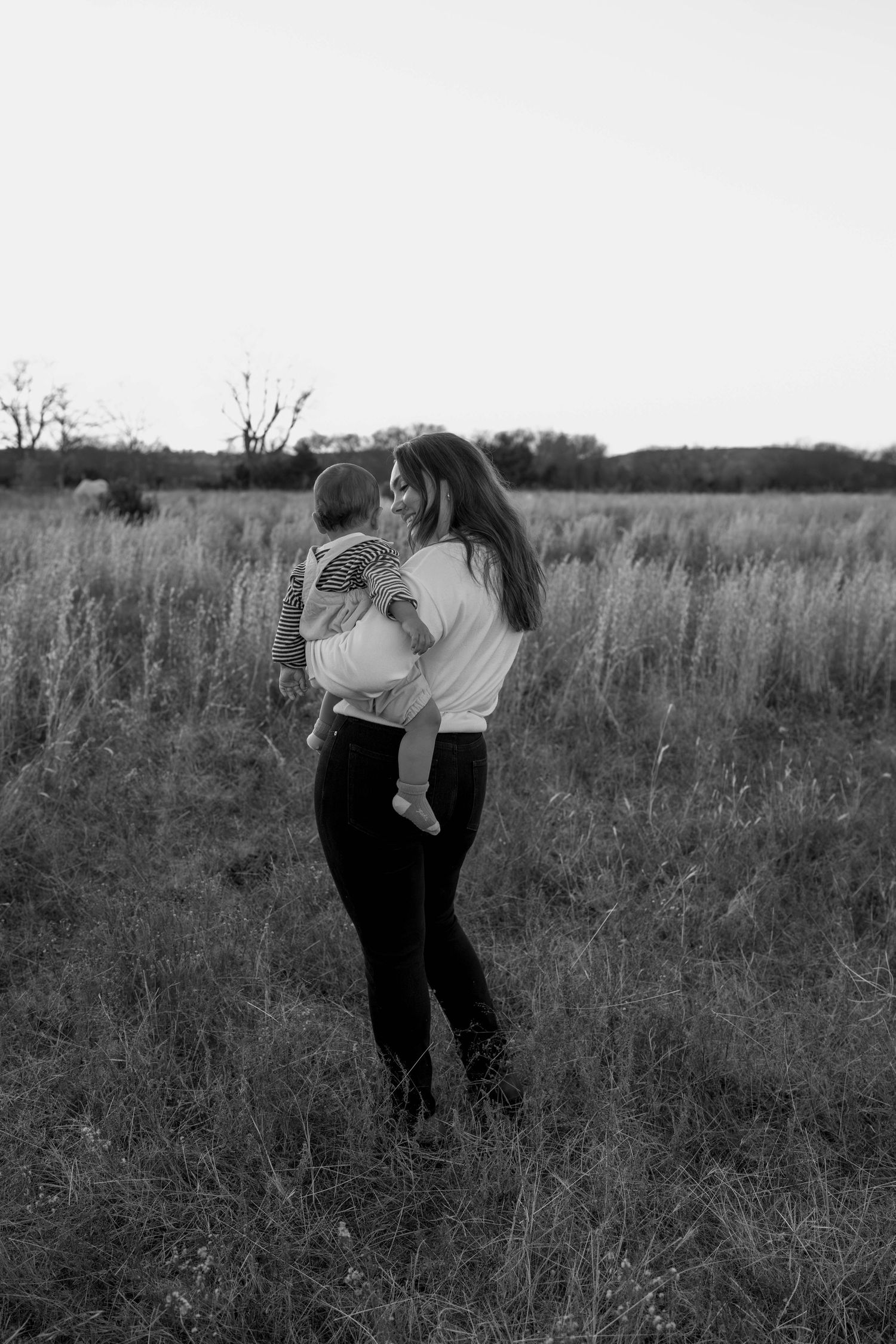 Couple dancing together in a field at sunset with romantic silhouettes.
