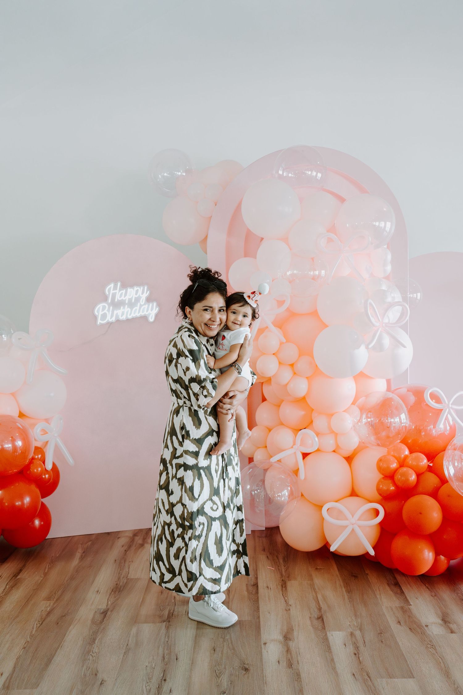 Birthday photoshoot featuring elegant balloon decor in coral and pink tones.