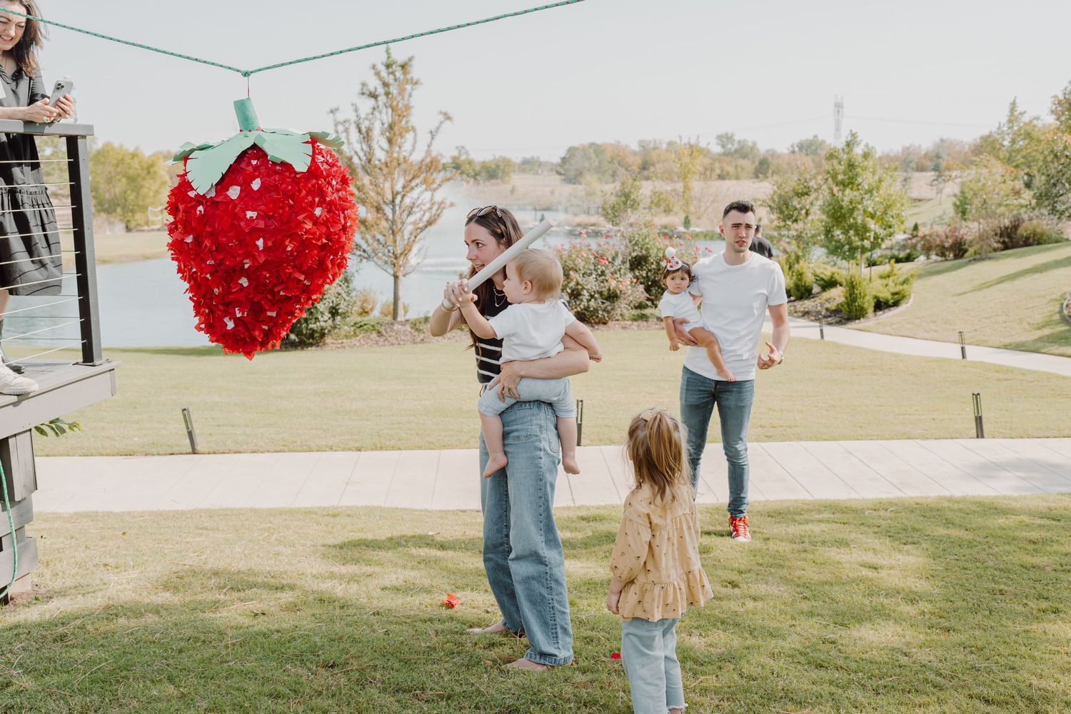 People gather on a grassy hillside with a red heart balloon display visible in the background.