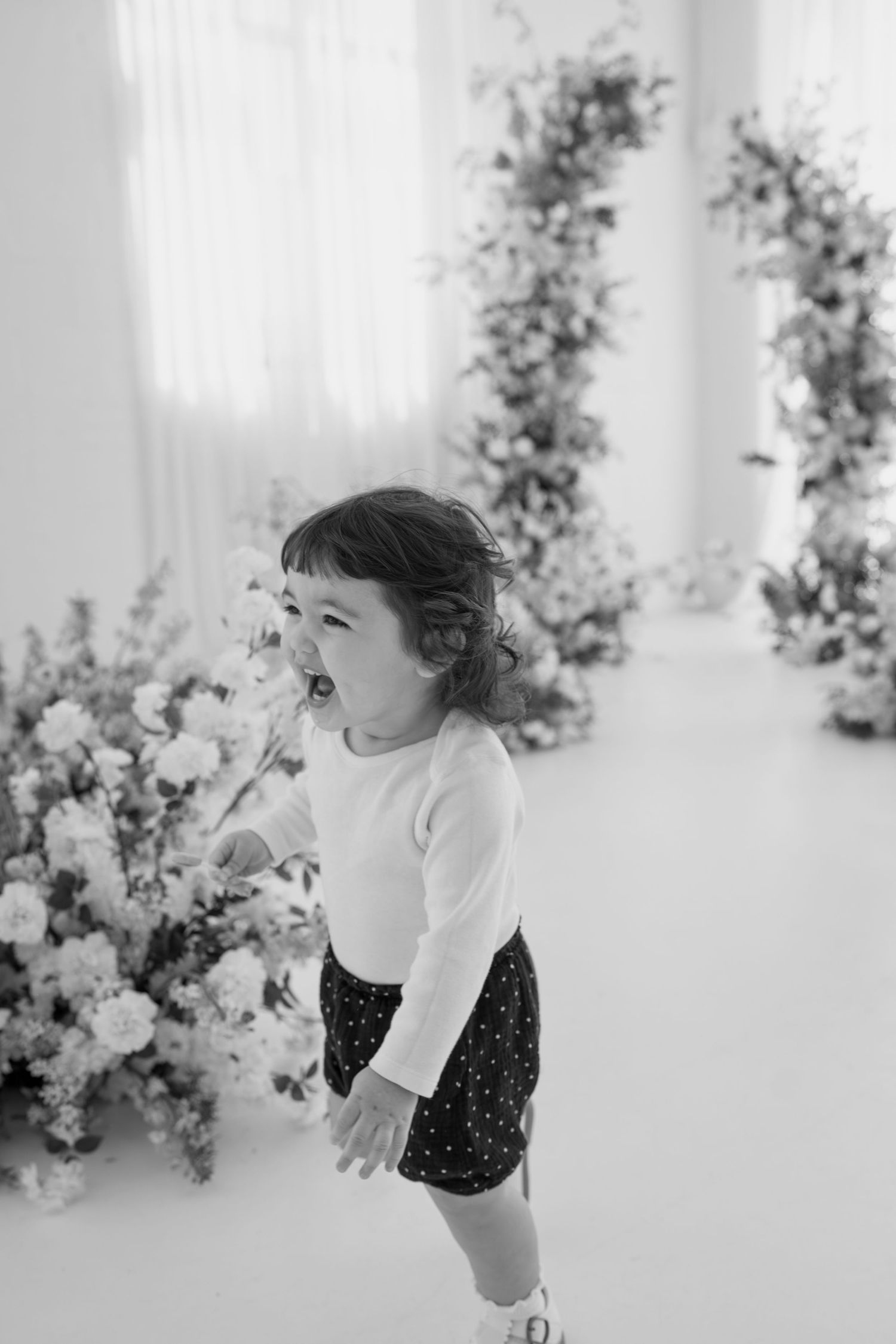 Black and white series showing expressive moments in an elegant studio setting with floral decor.