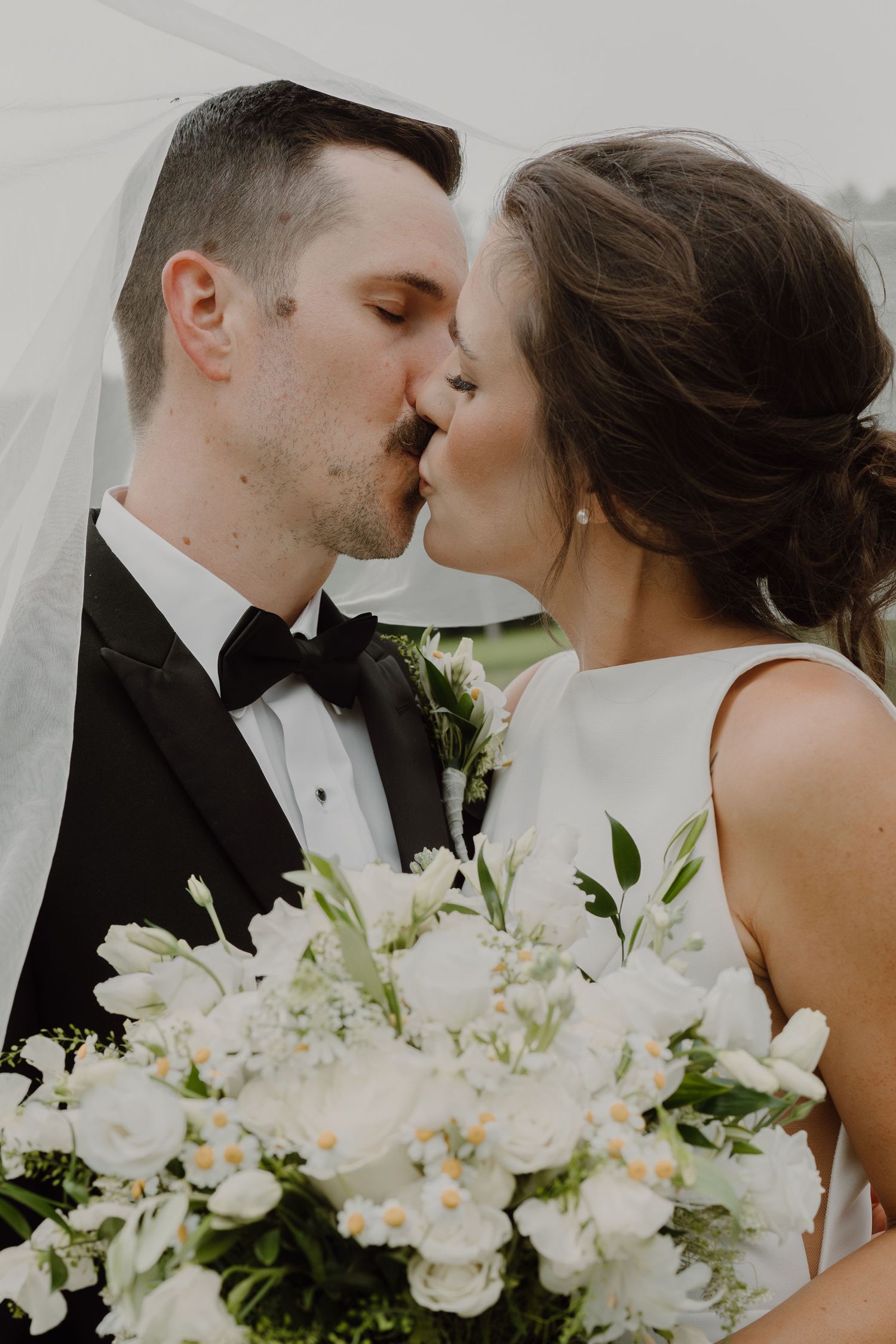 Romantic wedding moment with white floral bouquet and elegant attire.