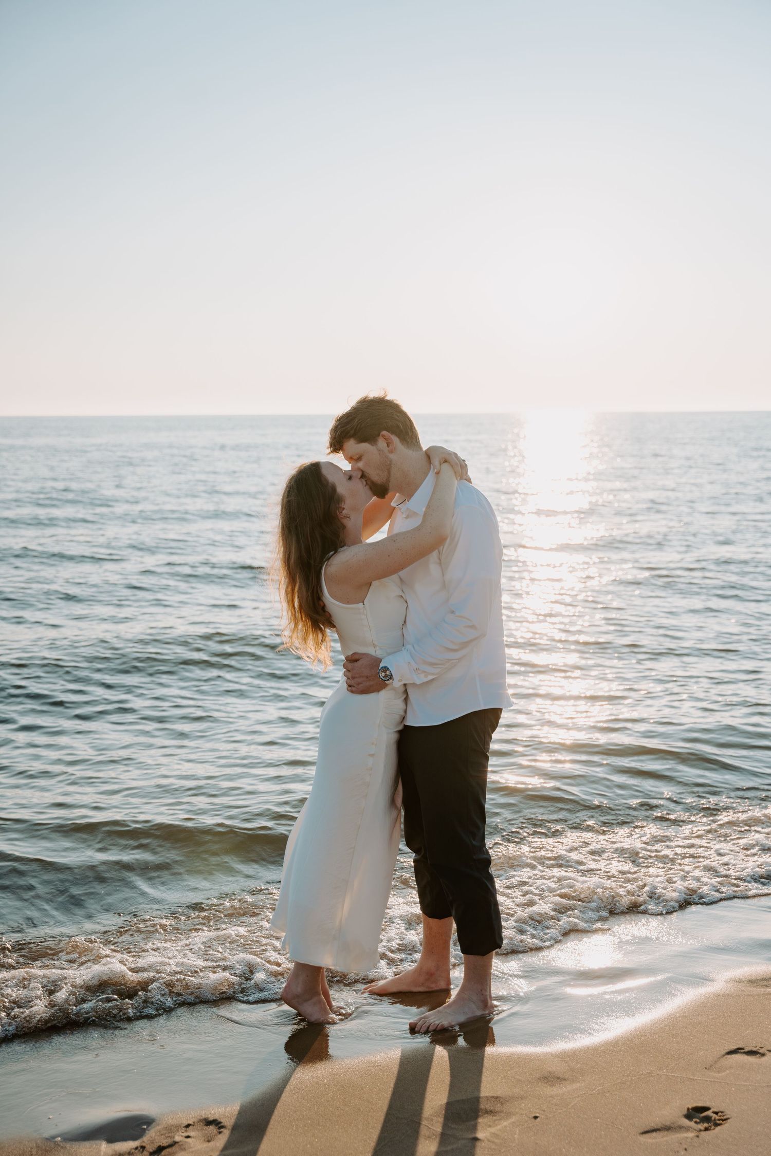 A couple shares an intimate moment on the beach during golden hour.