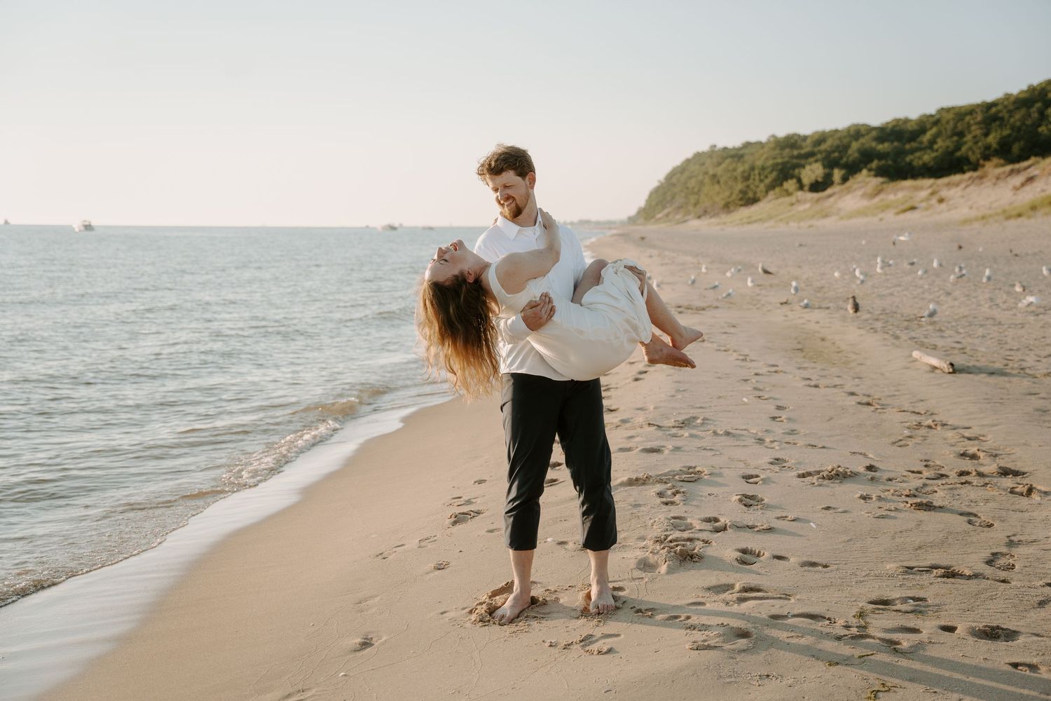 Joyful beach photography session with couple against coastal backdrop.