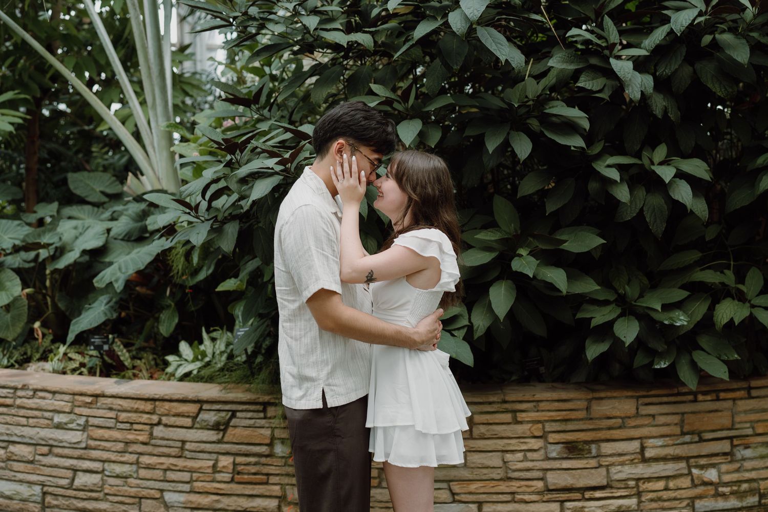 Romantic sequence of a couple in a lush garden setting with stone walls.