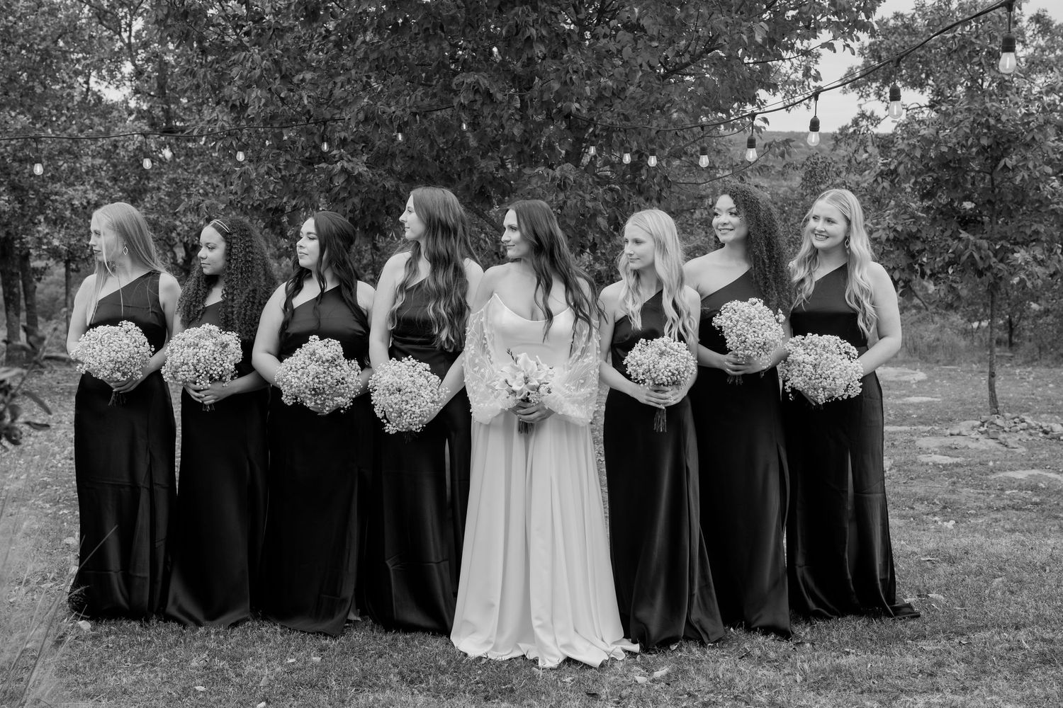 Wedding party in black and white dresses gather for group photos in a fall outdoor setting.