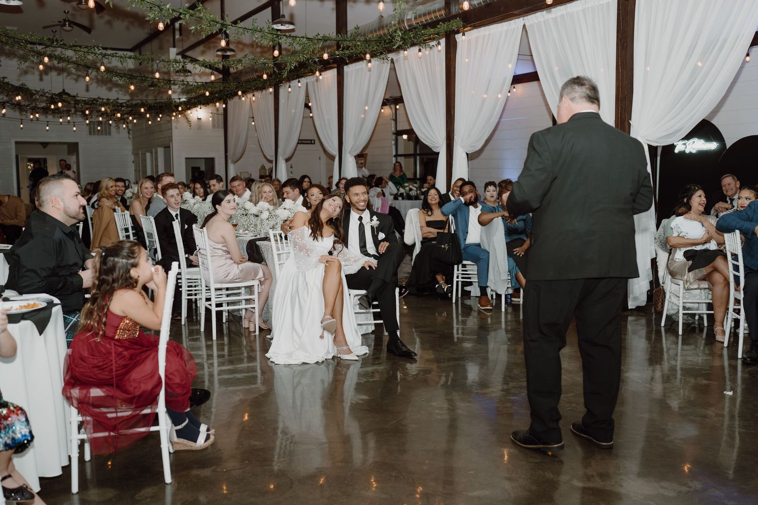 Wedding reception space featuring industrial elements and soft white drapery accents.