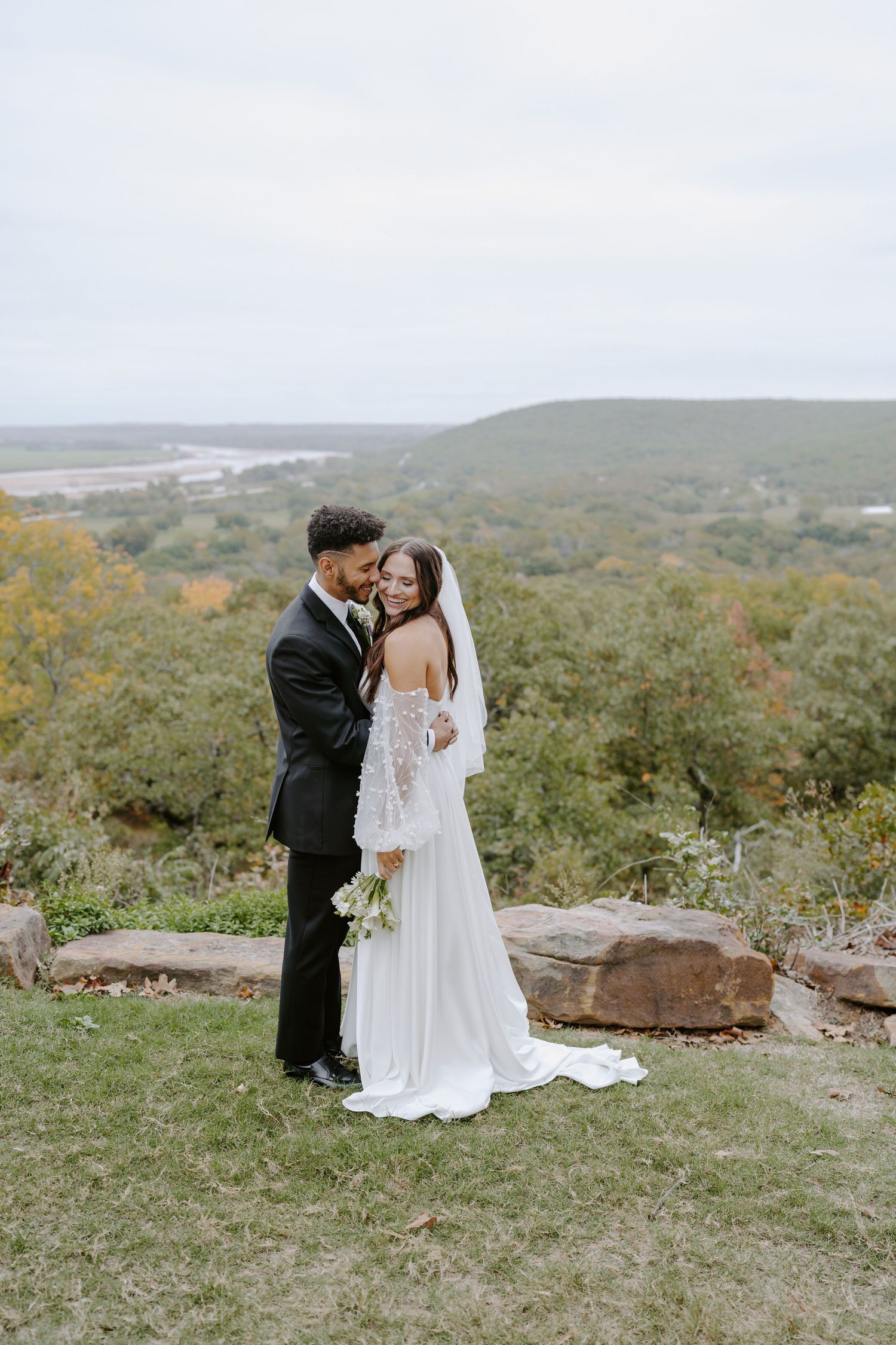 An elegant outdoor wedding photoshoot featuring a scenic mountain backdrop and natural landscape.