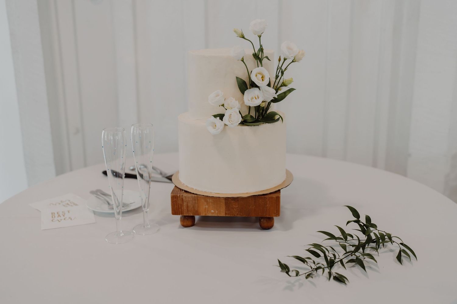 Minimalist white wedding reception setup with delicate floral arrangements.