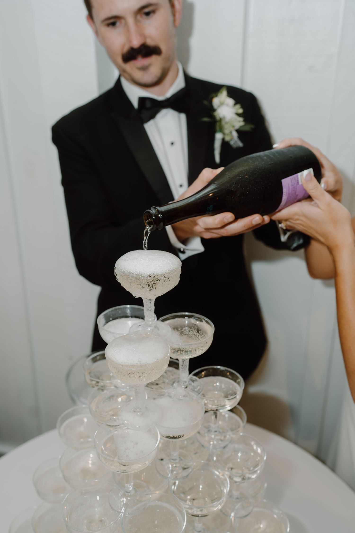 Close-up of champagne being carefully poured into a tower of crystal glasses.