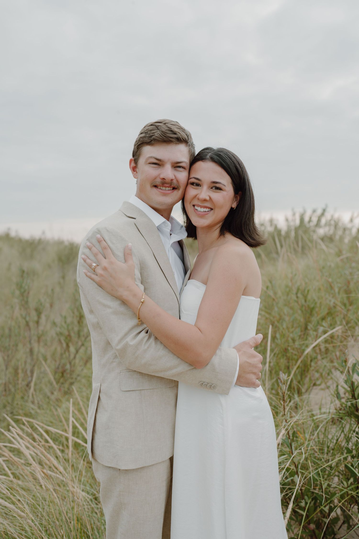 Happy couple sharing laughs and embraces during their beach wedding photo session.