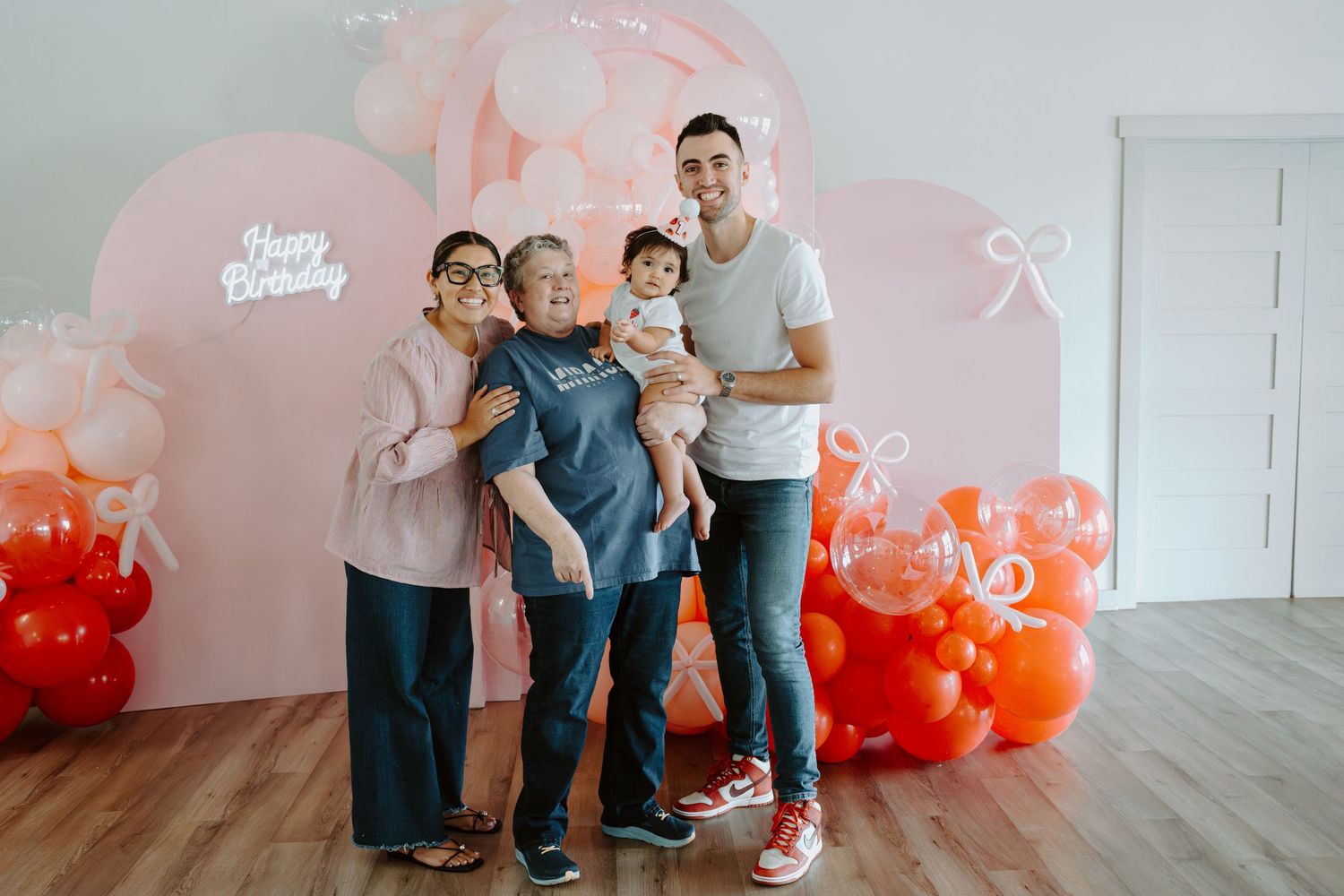 Candid family photo session with vibrant orange balloon decorations in a bright studio space.