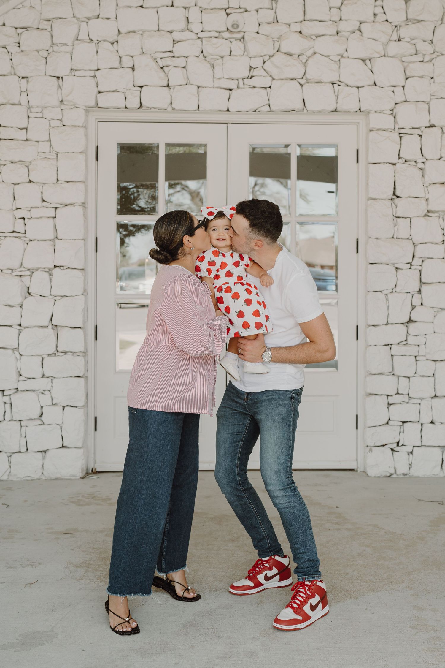 Candid moments captured against white stone wall with glass door backdrop.