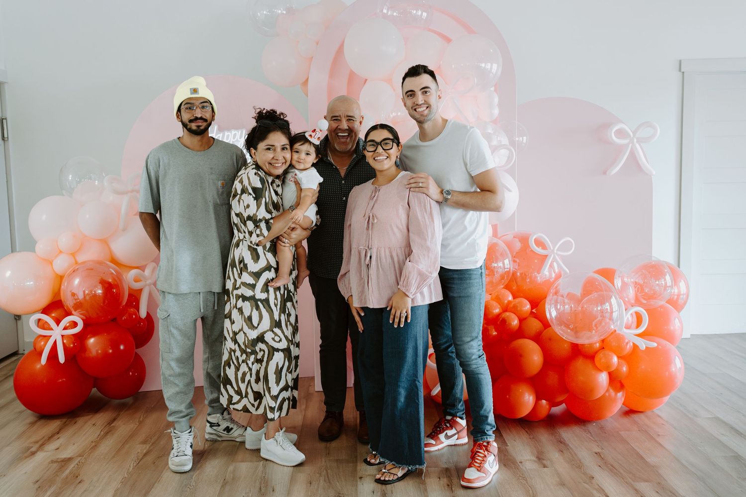 Group photo against a white wall decorated with an ombre balloon installation.