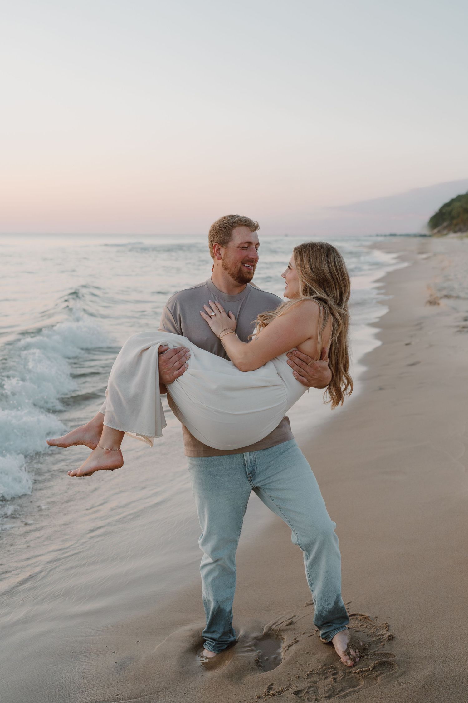 A romantic beach photoshoot shows a couple playing in the sand during golden hour.