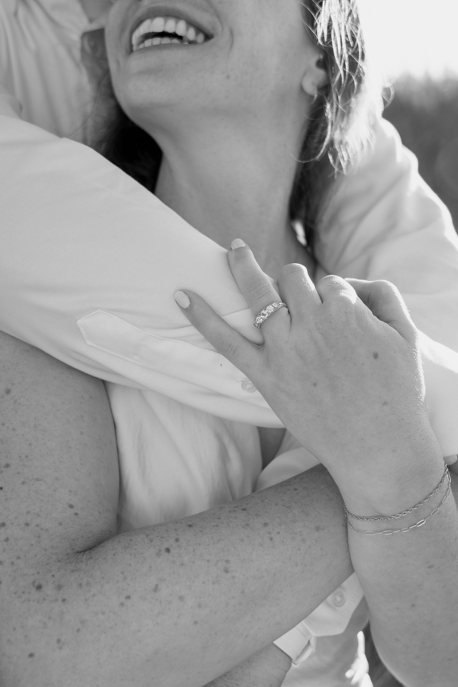 Close-up black and white photo showing hands and jewelry against white fabric.