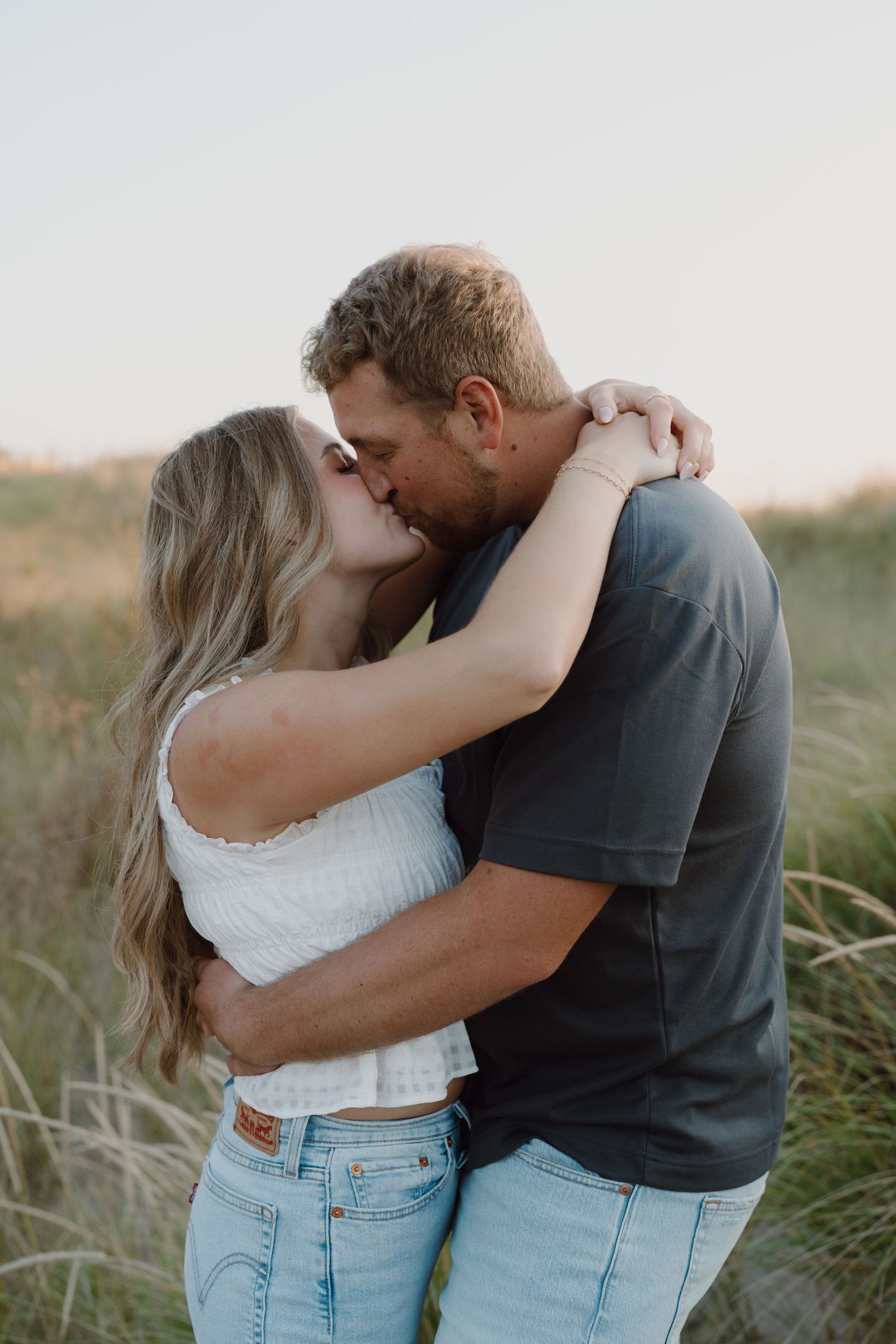 Intimate couple's portrait showing tender embrace against natural beach landscape.