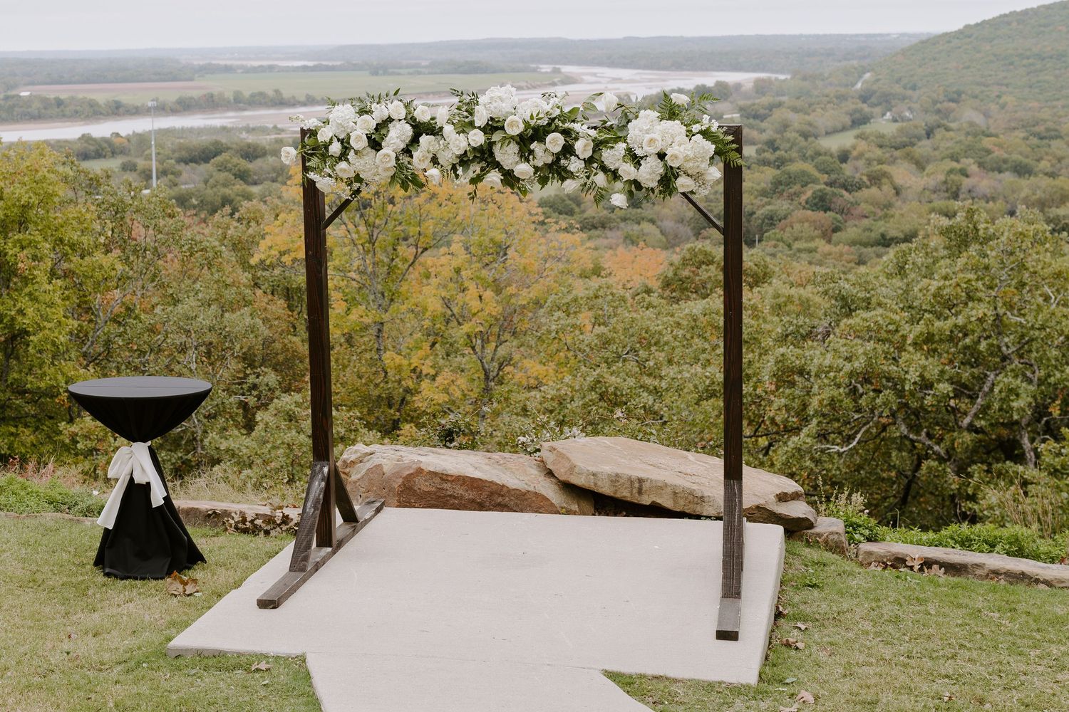 Scenic hilltop wedding venue overlooking a vast landscape with white chairs set up for ceremony.