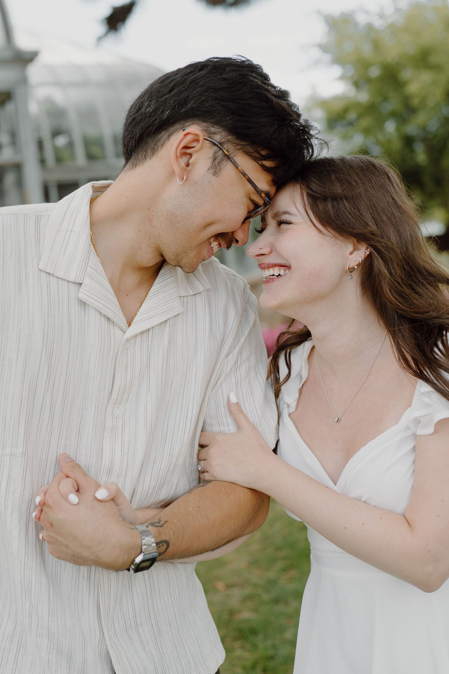 A playful couple shares joyful moments together against a white fence backdrop.