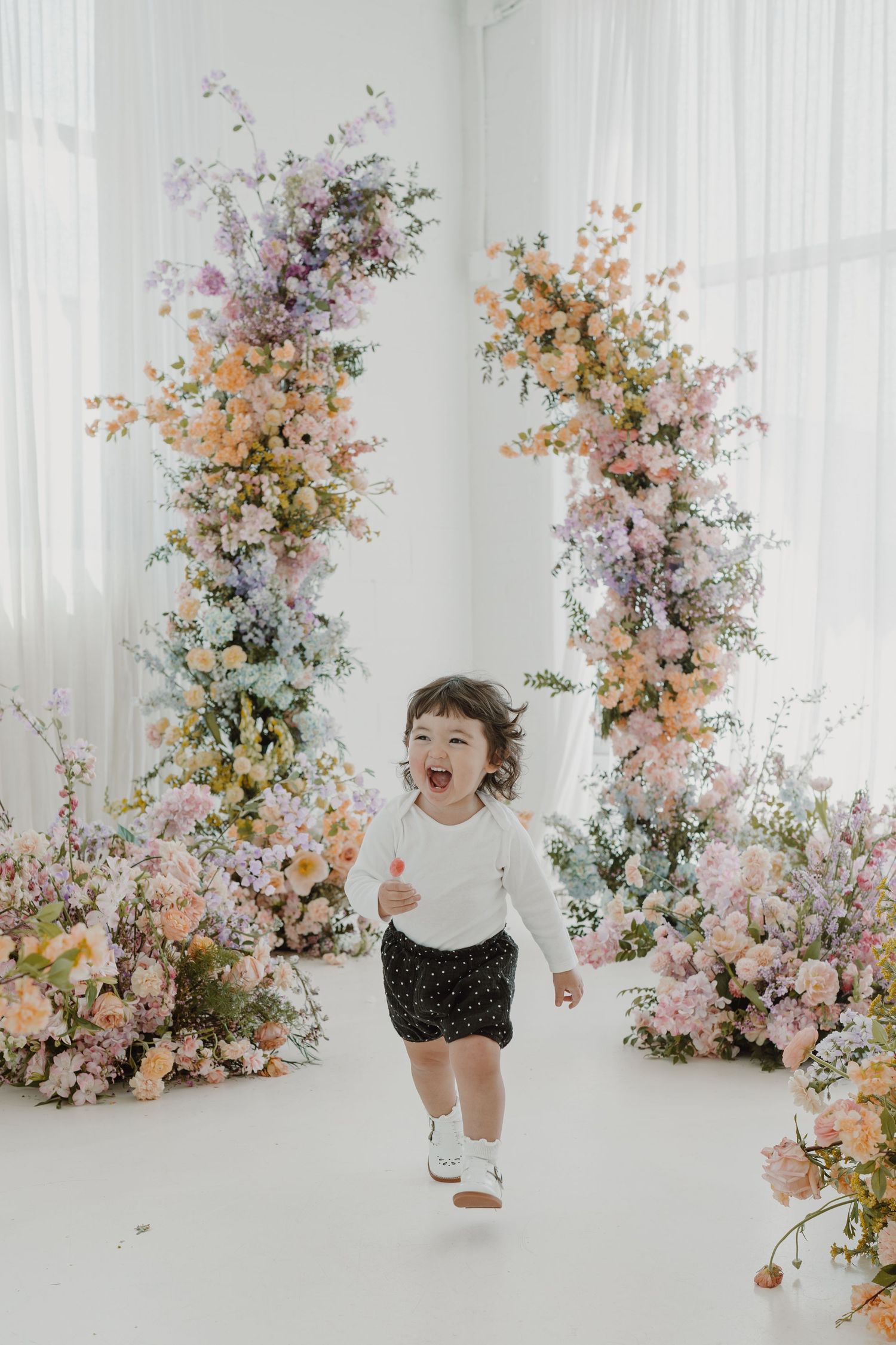 Energetic movement captured in a white studio space adorned with romantic floral installations.
