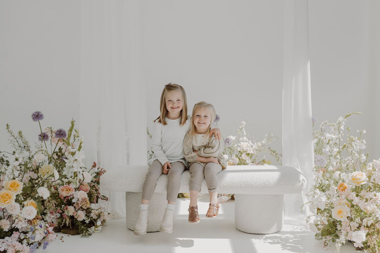 Elegant white studio setup featuring ceramic vessels and wildflower arrangements in natural light.