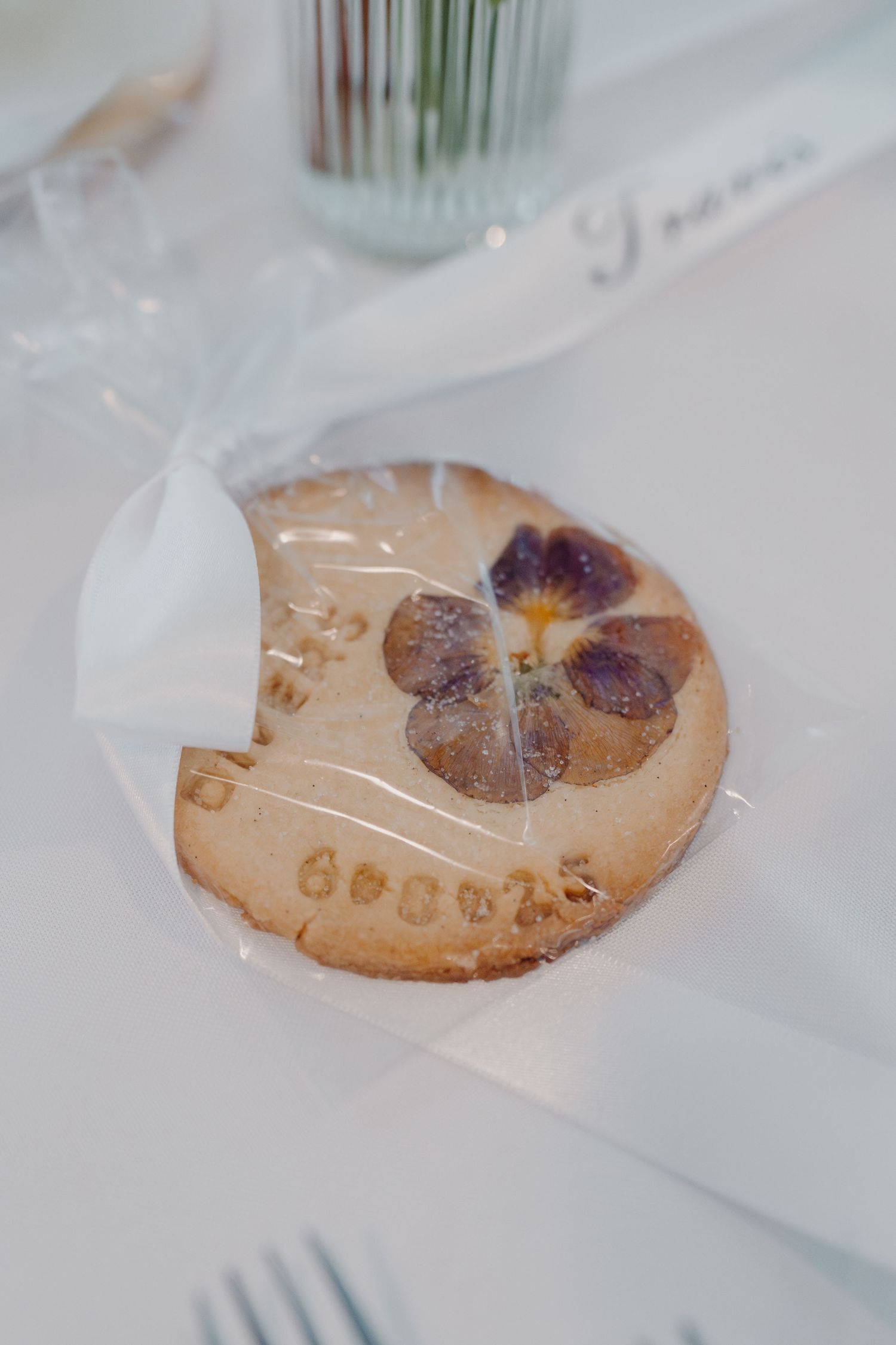 Close-up of pressed dried flowers decorating a handmade cookie or biscuit on white surface.